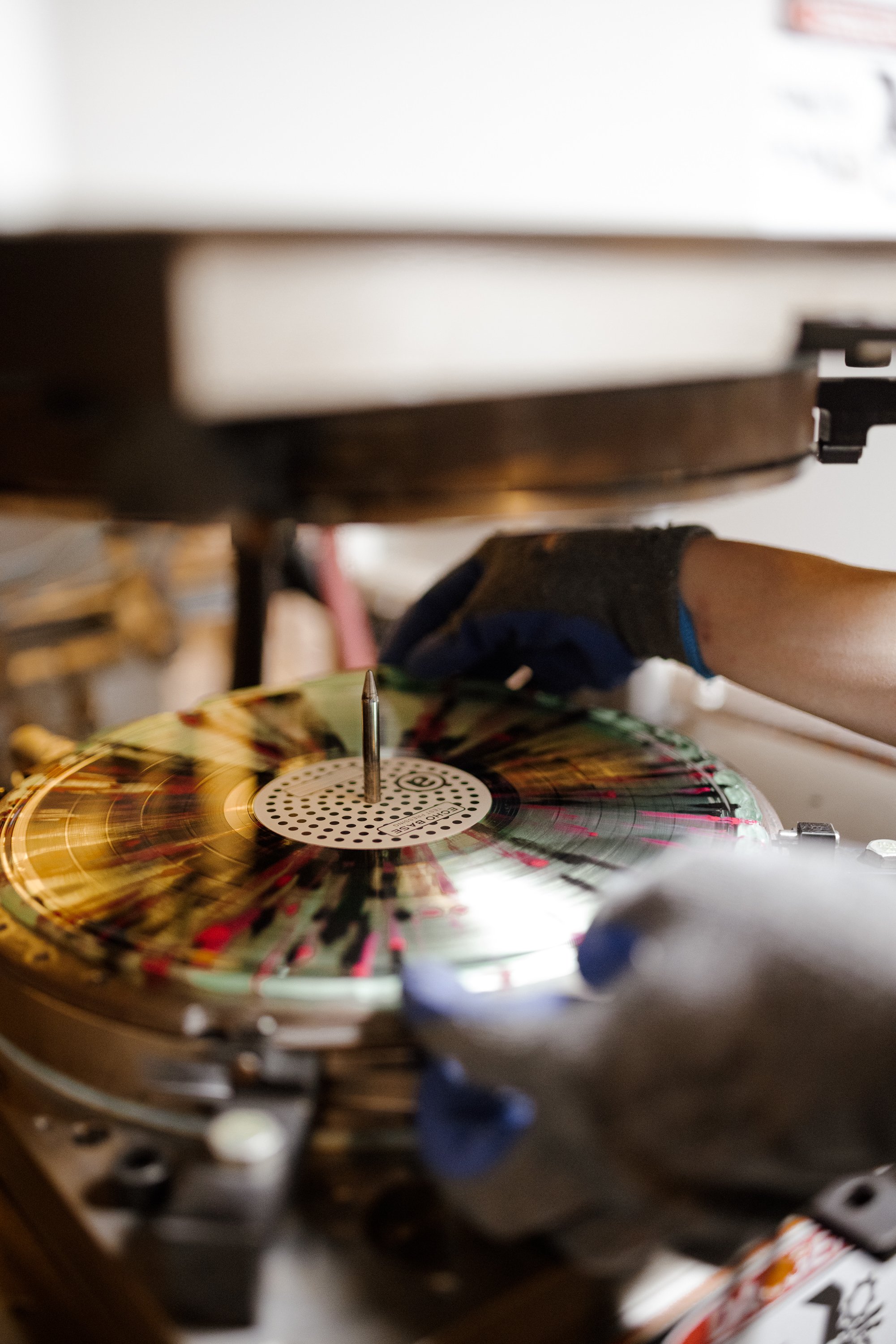 A person wearing gloves is placing a vinyl record onto a turntable. Echo Base Athens Ga