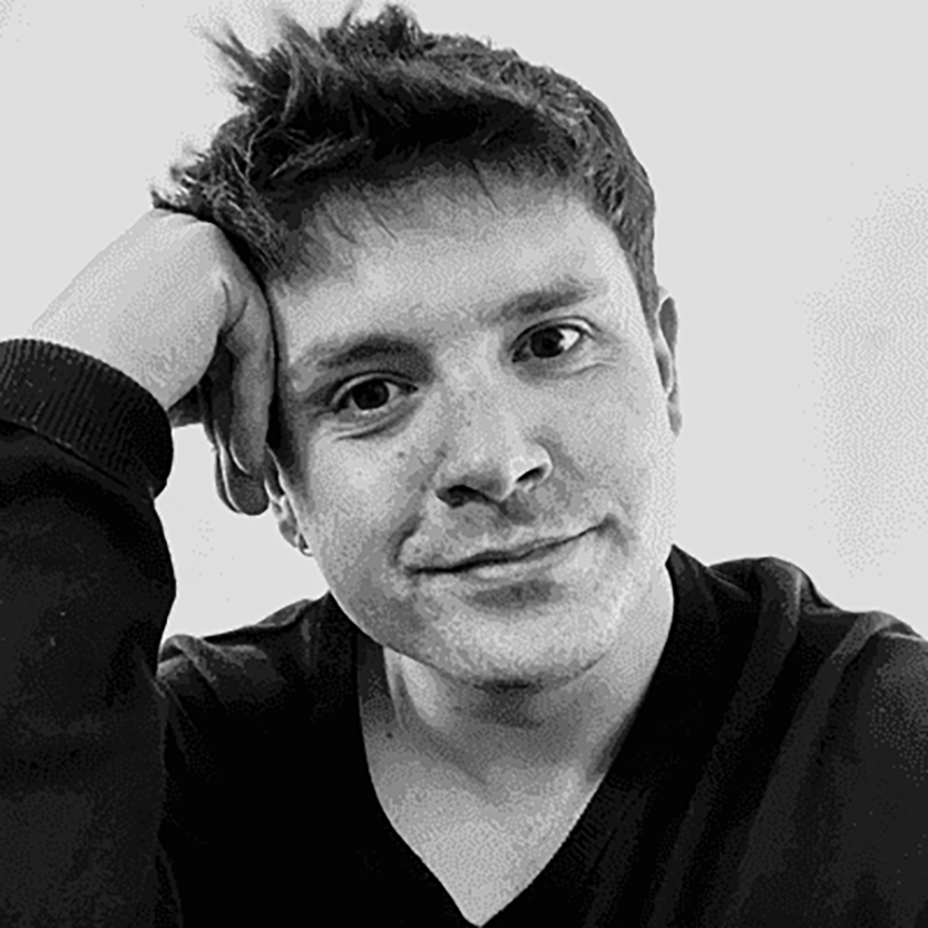 Young man with short hair resting his head on his hand, smiling slightly, wearing a dark shirt, in black and white.