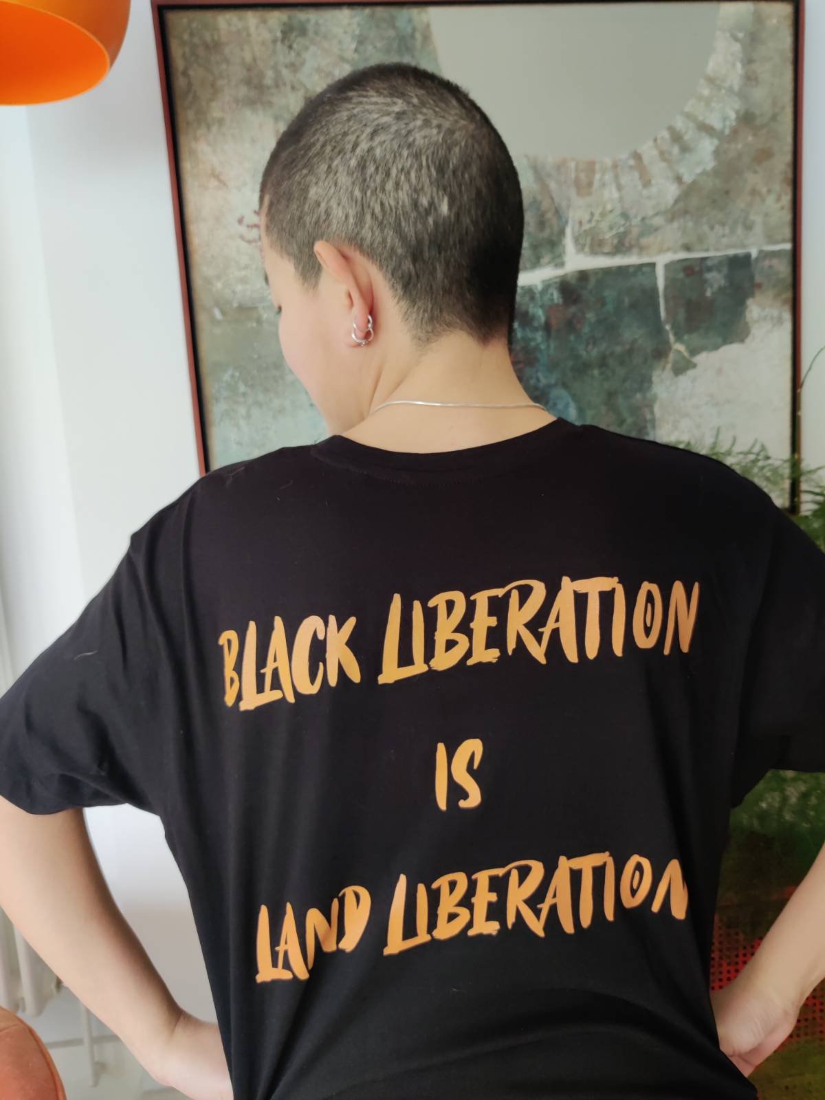 Back of the black t-shirt says 'Black Liberation is Land Liberation'.