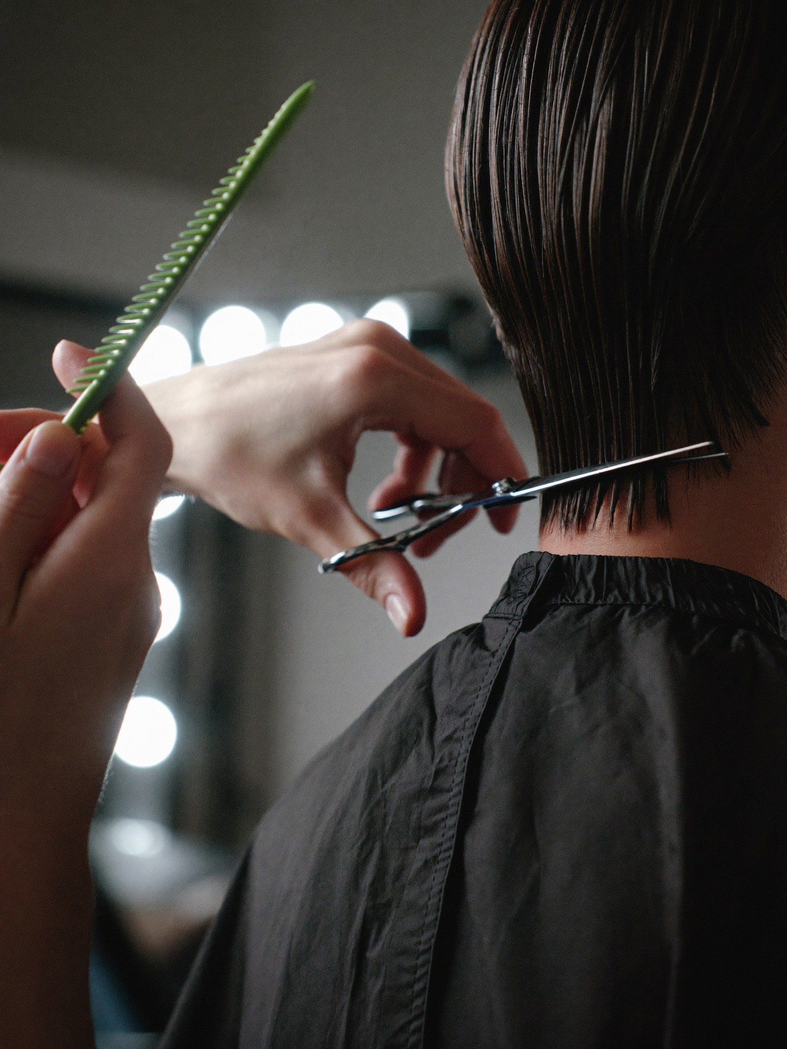 Hairdresser cutting a person's hair with scissors in a salon.