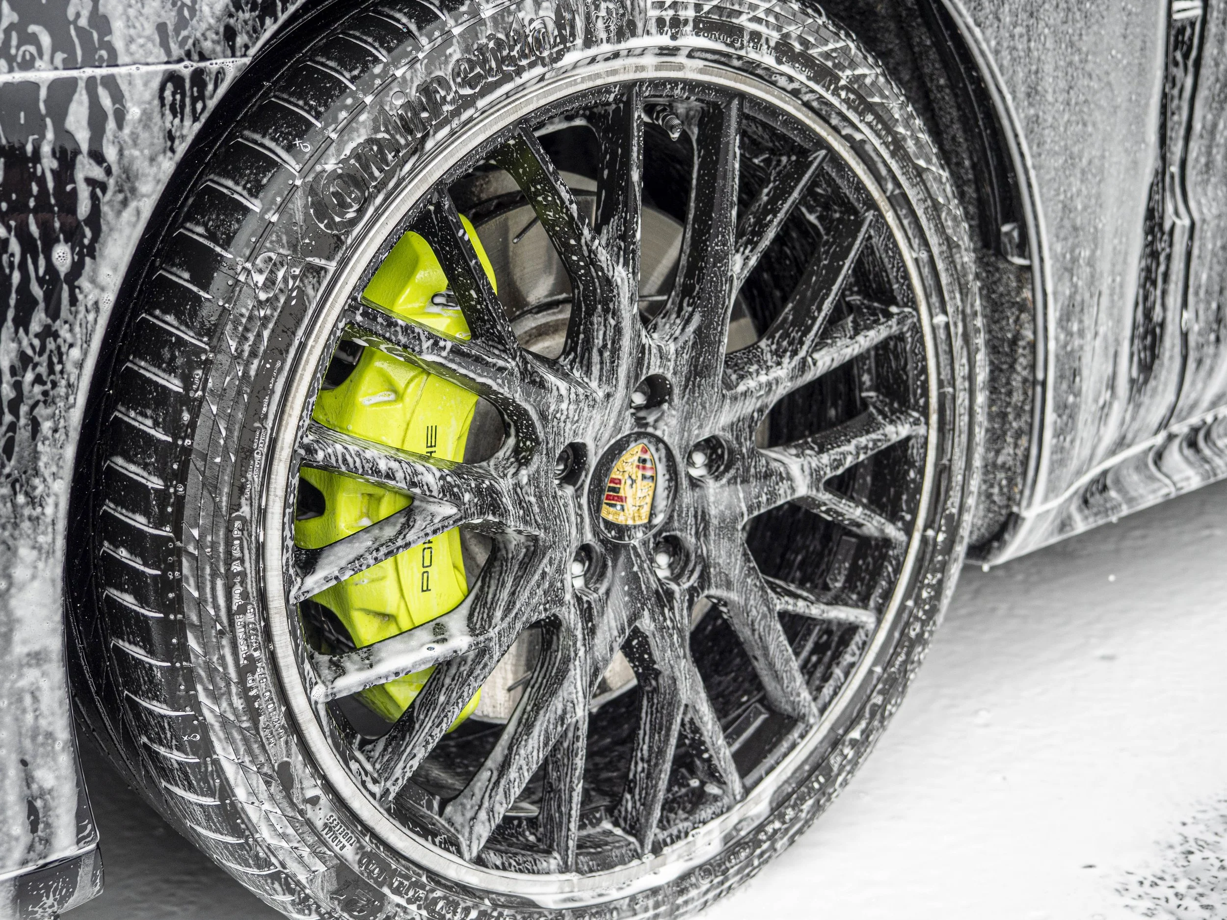 Snow foam on wheels of a Porsche Panamera E Hybrid ready to be cleaned.