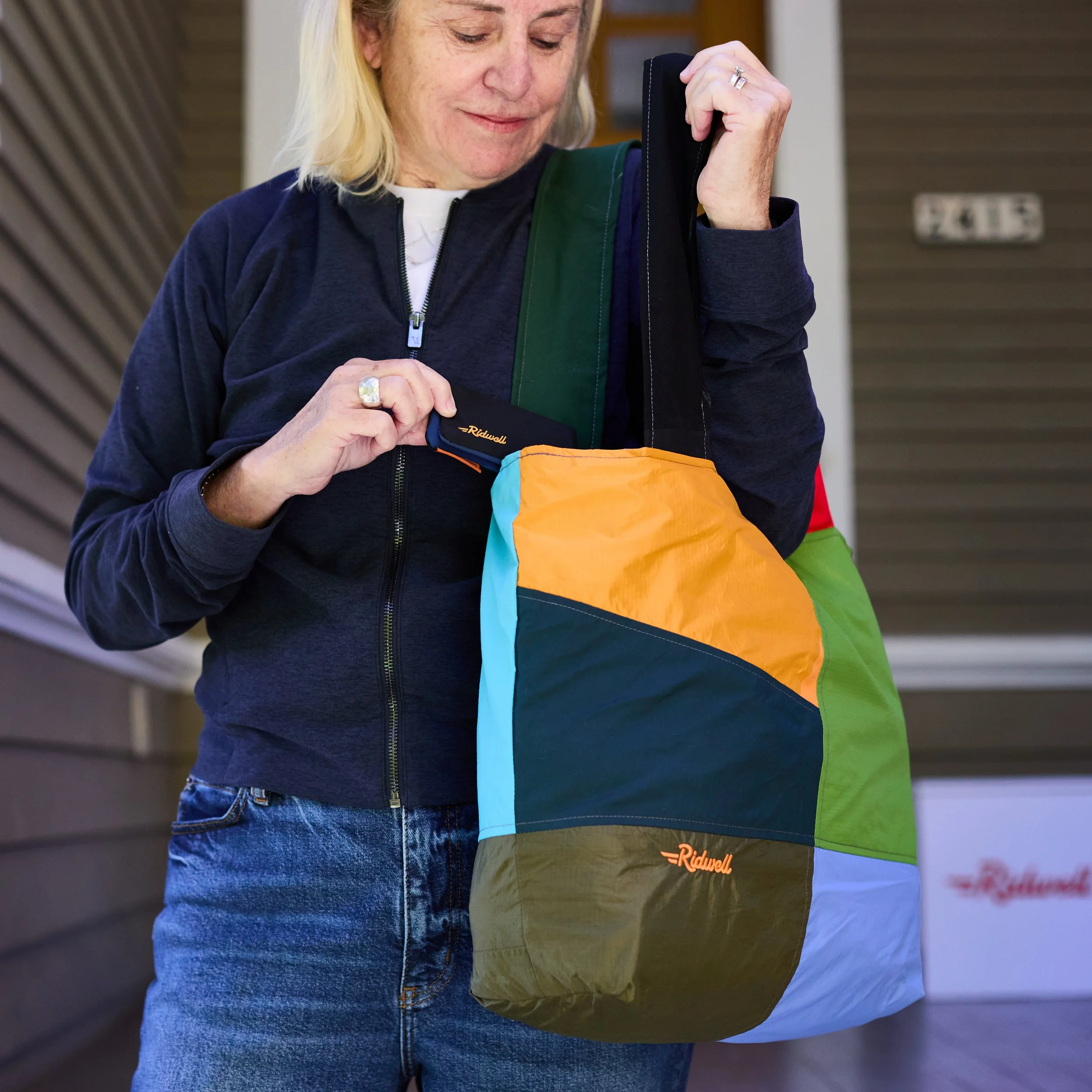 Smiling woman with bag and wallet made out of upcycled outerwear