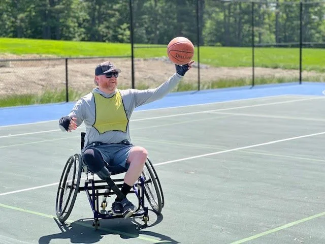 Man in a wheelchair playing wheelchair basketball on an outdoor court