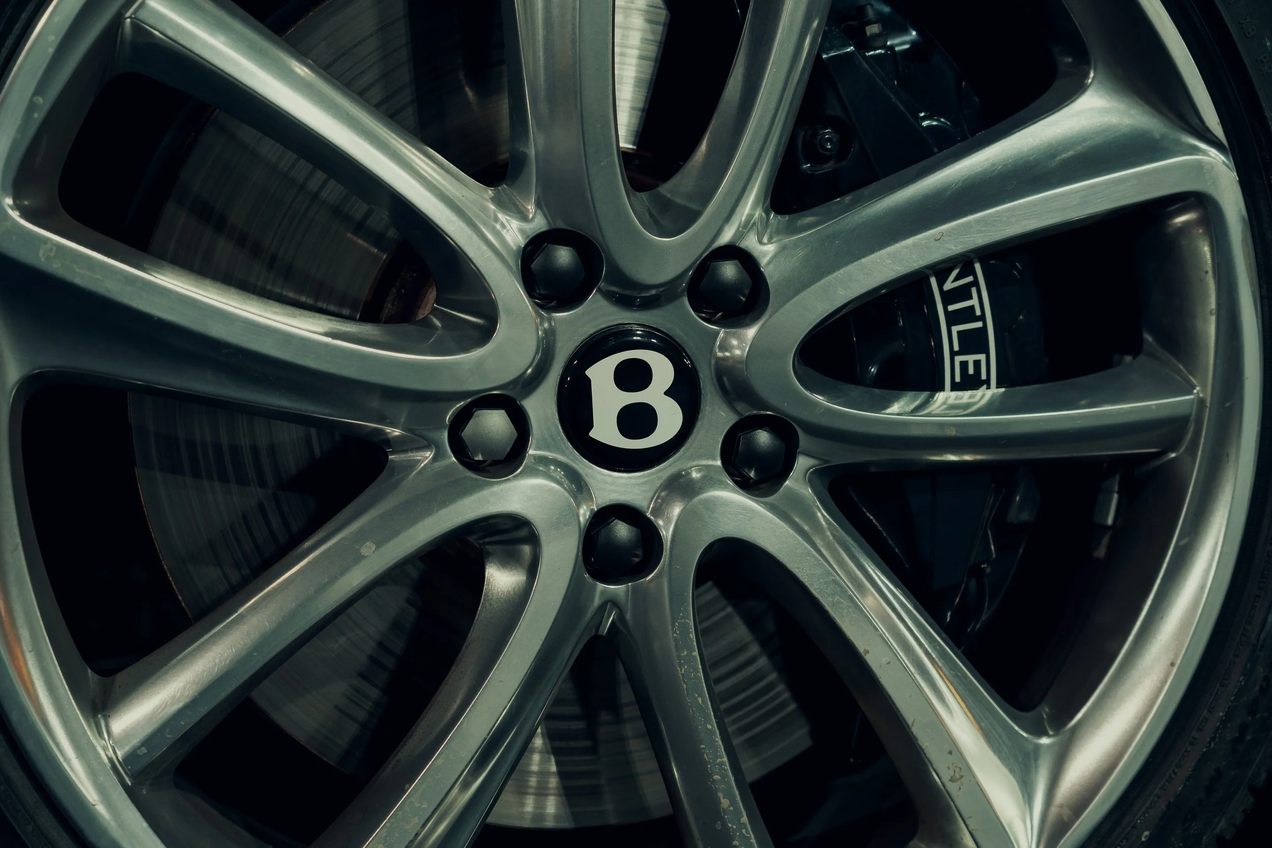 Close-up of a silver alloy wheel with Bentley branding.