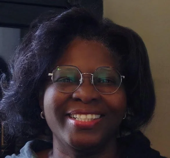 Photo of Miriam F. Williams wearing glasses and smiling in front of a bookcase.
