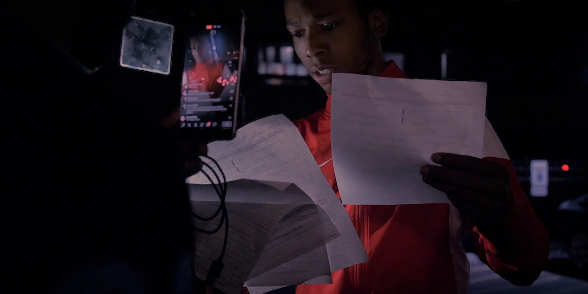 Two people looking at papers inside a vehicle, with one person holding a smartphone.