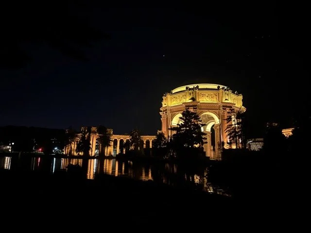Illuminated night view of the Palace of Fine Arts in San Francisco with reflections in the water.