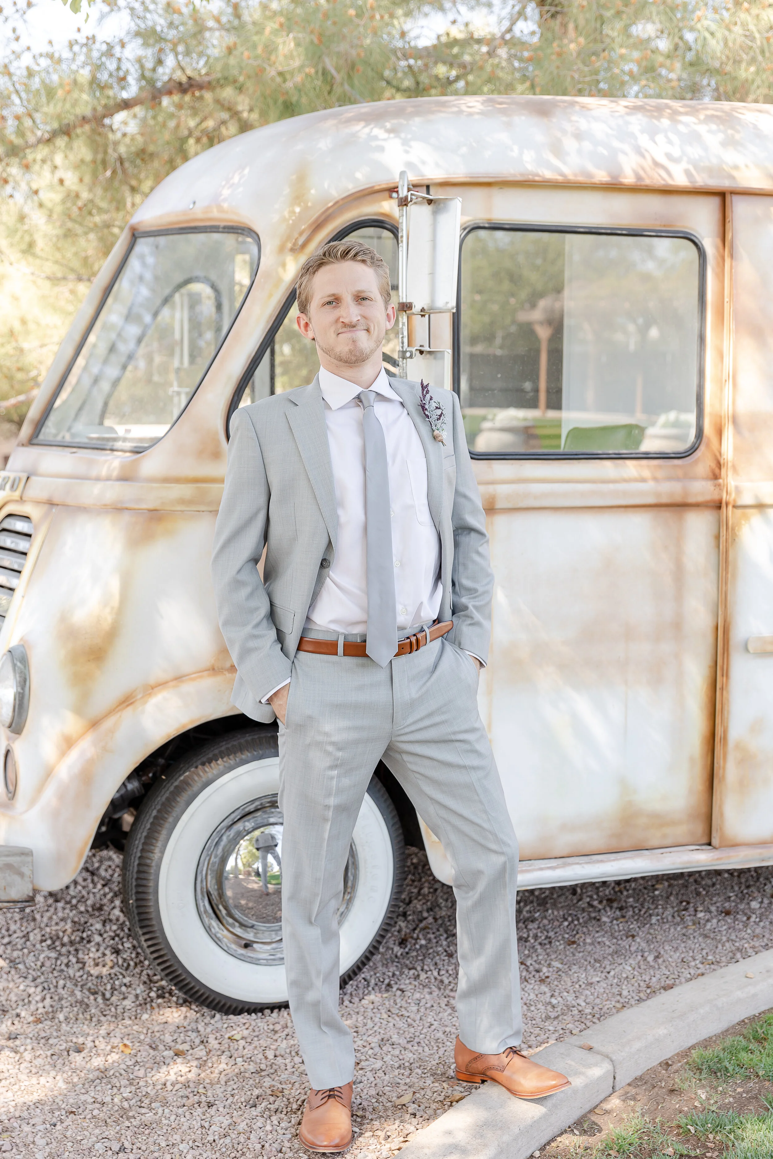 groom in gray suit with a vintage vehicle
