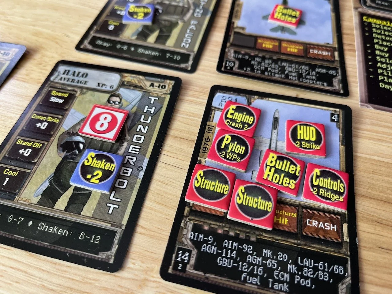 Closeup of Thunderbolt Apache Leader board game cards showing pilot card and a bunch of markers indicating a very shot-up A10-A he barely got home.