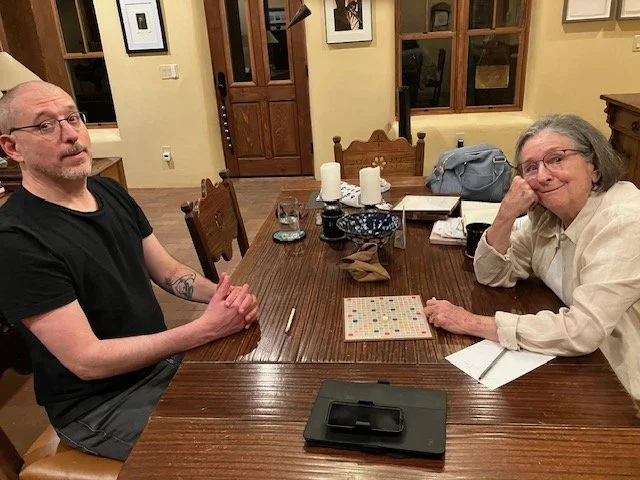 A nice-looking old lady prepares to cheat at Scrabble against her tired son.