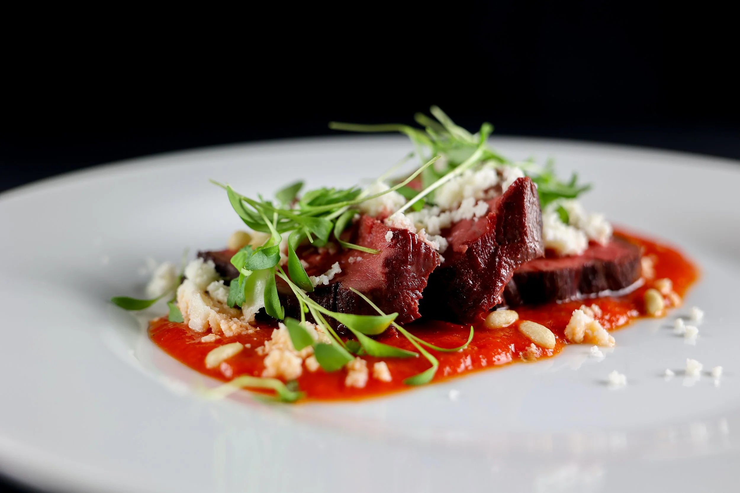 Black Pepper Crusted Chef's Cut of Beef in Ancho Rojo with pine nuts and queso fresco