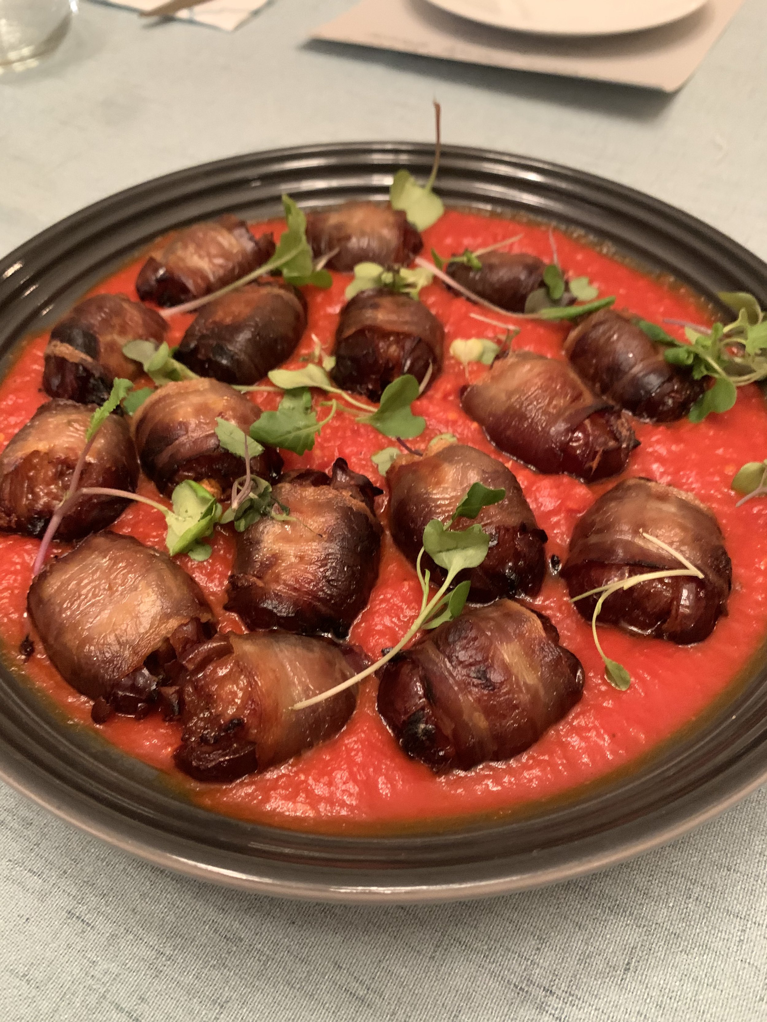 Chorizo stuffed and bacon wrapped dates in a roasted red pepper sauce