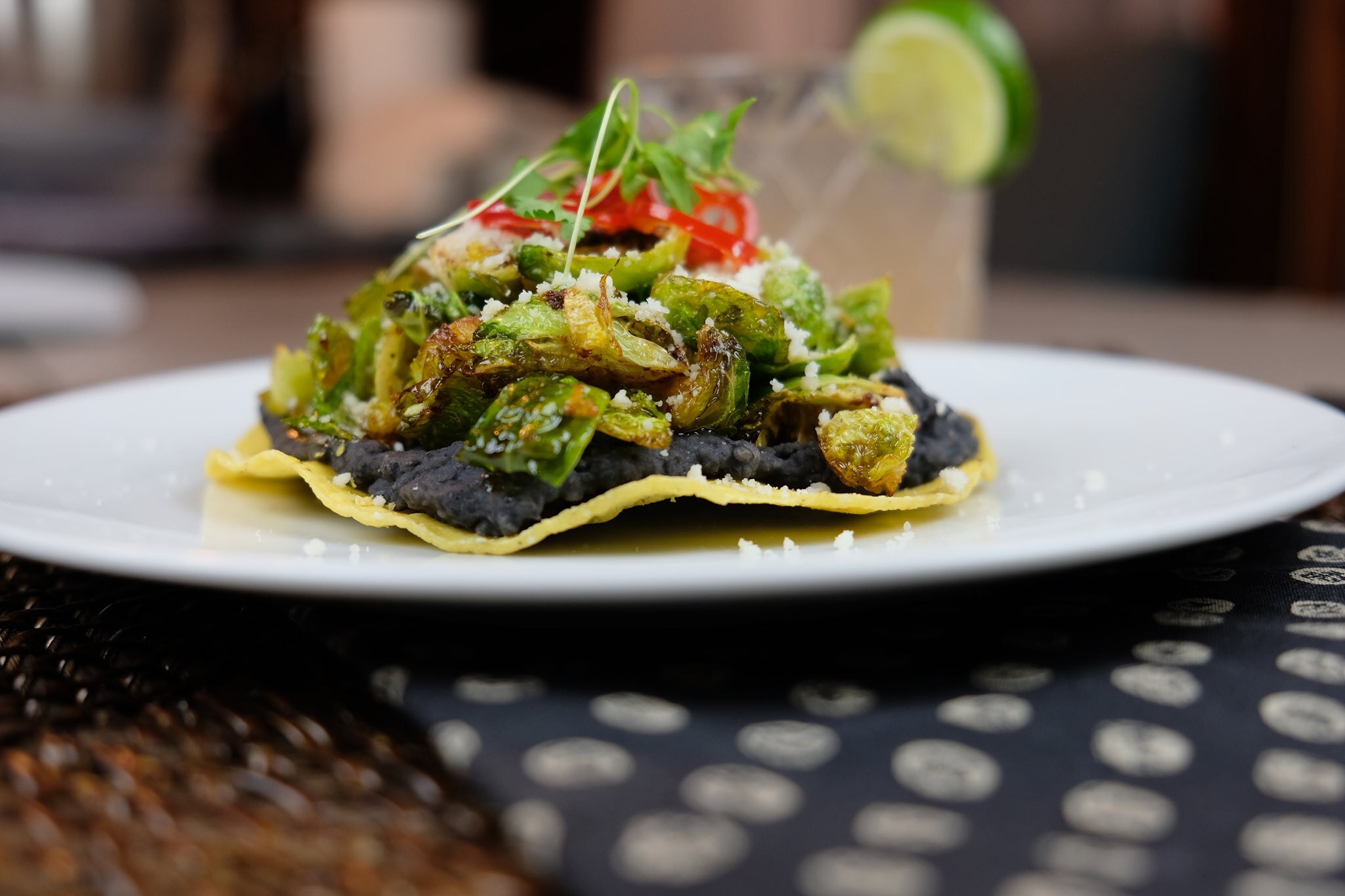 Brussel Sprout Tostada with black bean puree, pickled fresno, and queso fresco