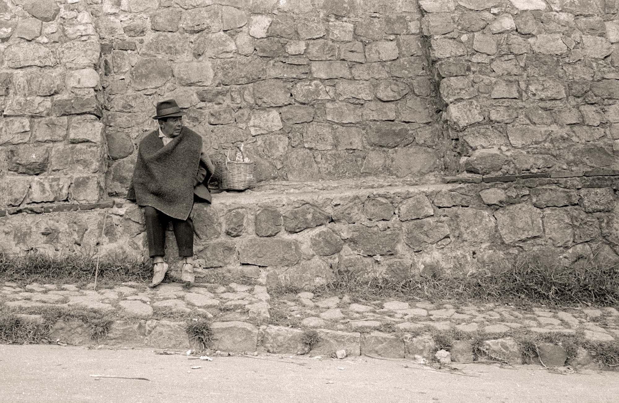 Man in Ruana Along a High Stone Wall