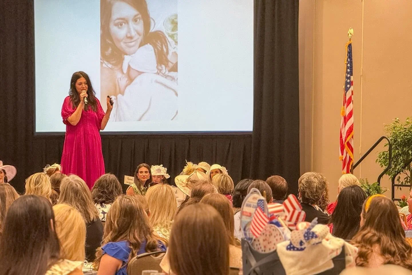 A woman speaking at a podium during an event celebrating 20 years of AWIA, with an audience in front and event banners visible.