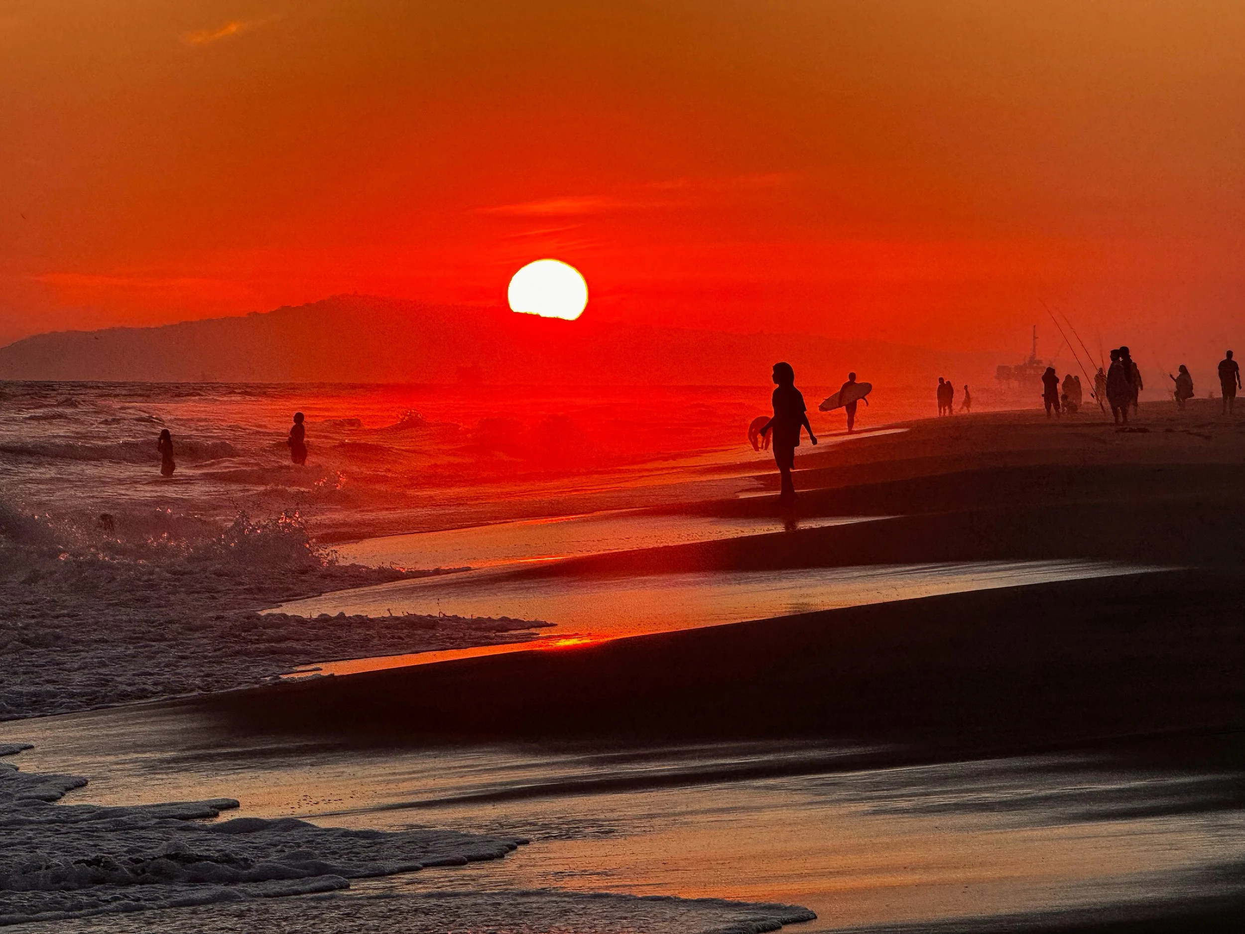 surfers and beachgoers at sunset on beach