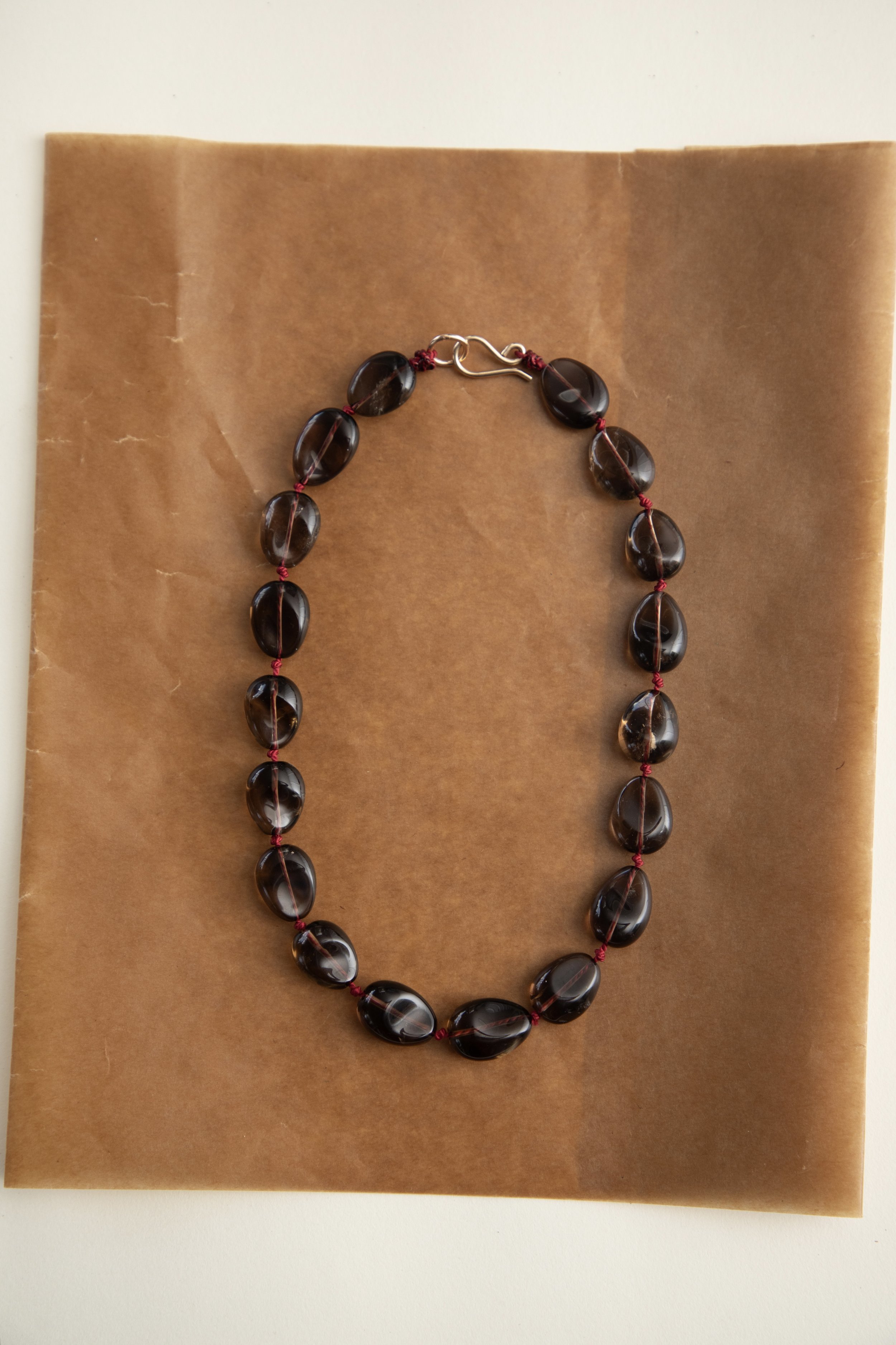 Polished concave smoky quartz bead detail on red silk necklace