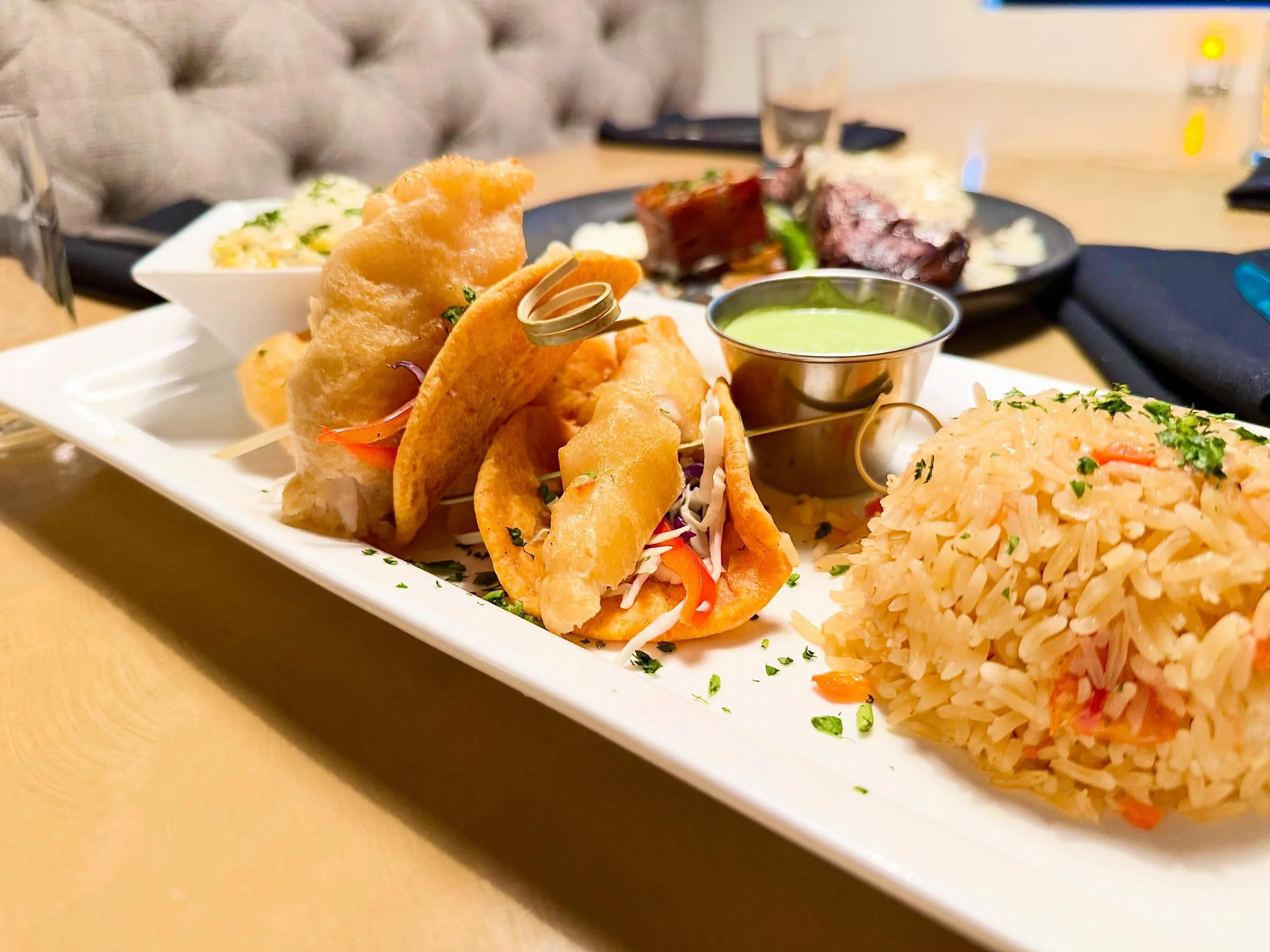 One of our delicious features!
Baja Fish Tacos:
Beer-battered Icelandic cod on house-made roasted red pepper flour tortillas with fresh vegetable slaw and poblano crema. Served with truffle street corn and Mexican rice.

Make your reservation on our 