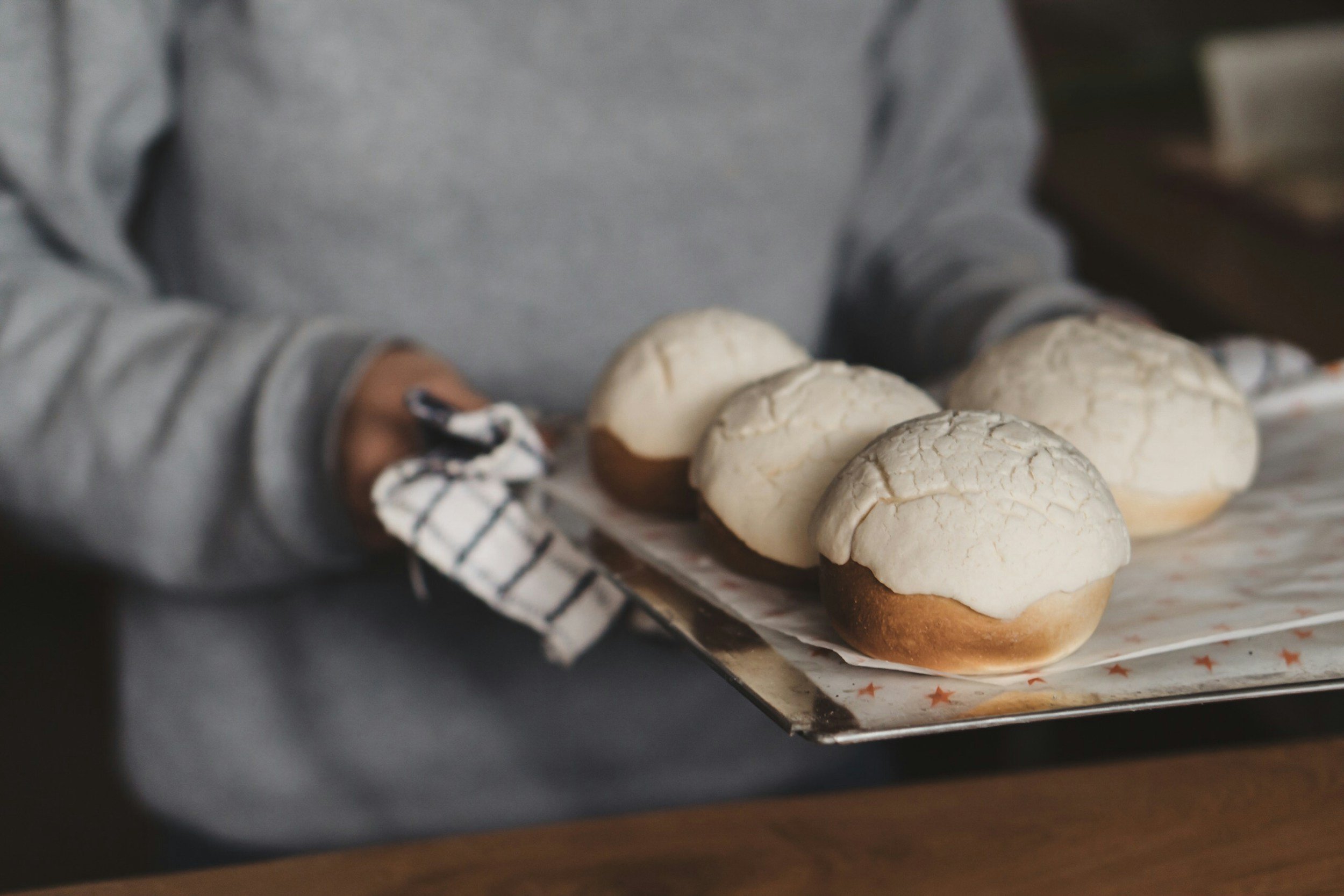 Woman holding a tray of baked goods fresh out of the oven.