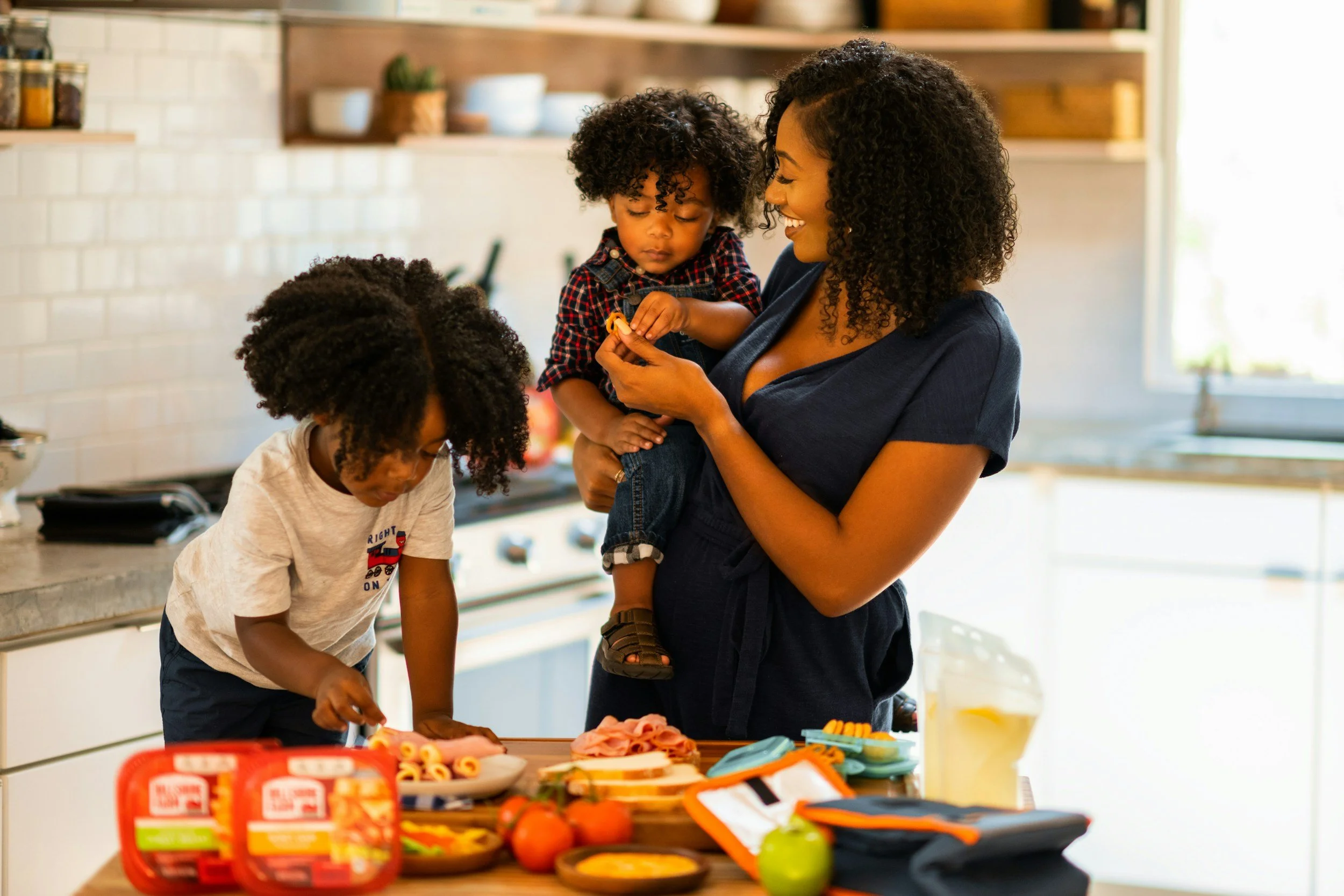 Mother prioritizing her two young kids by spending quality time creating recipes in the kitchen.