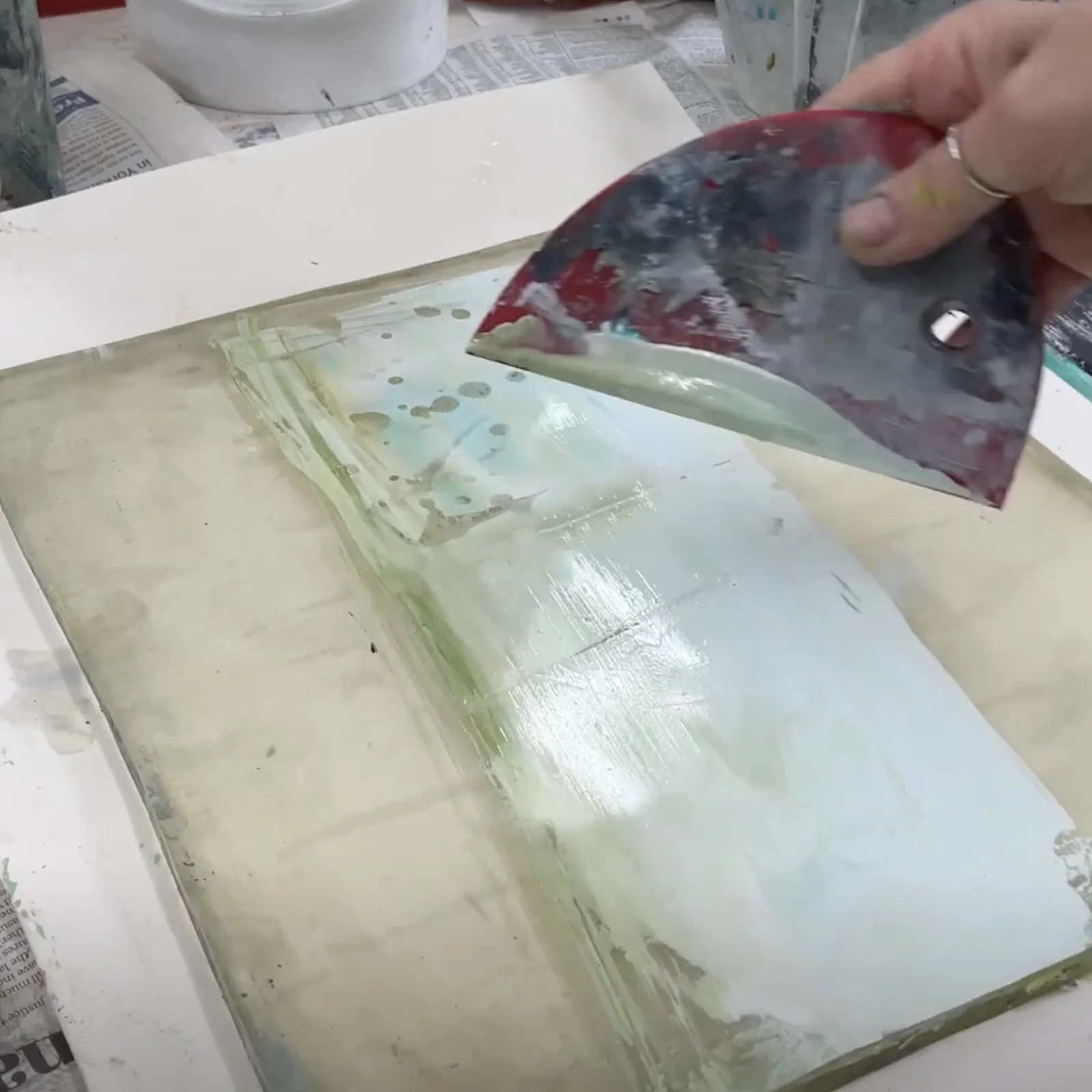 Artist using a Messermeister silicone bowl scraper for mark-making, scraping paint and creating texture in mixed media artwork