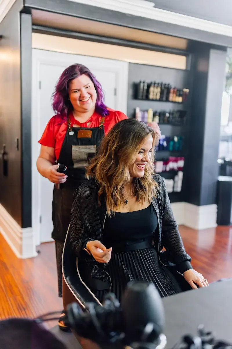 Stylist at The State Co in Livermore, CA smiling with a guest after a fresh haircut and style in the salon’s bright, welcoming space.