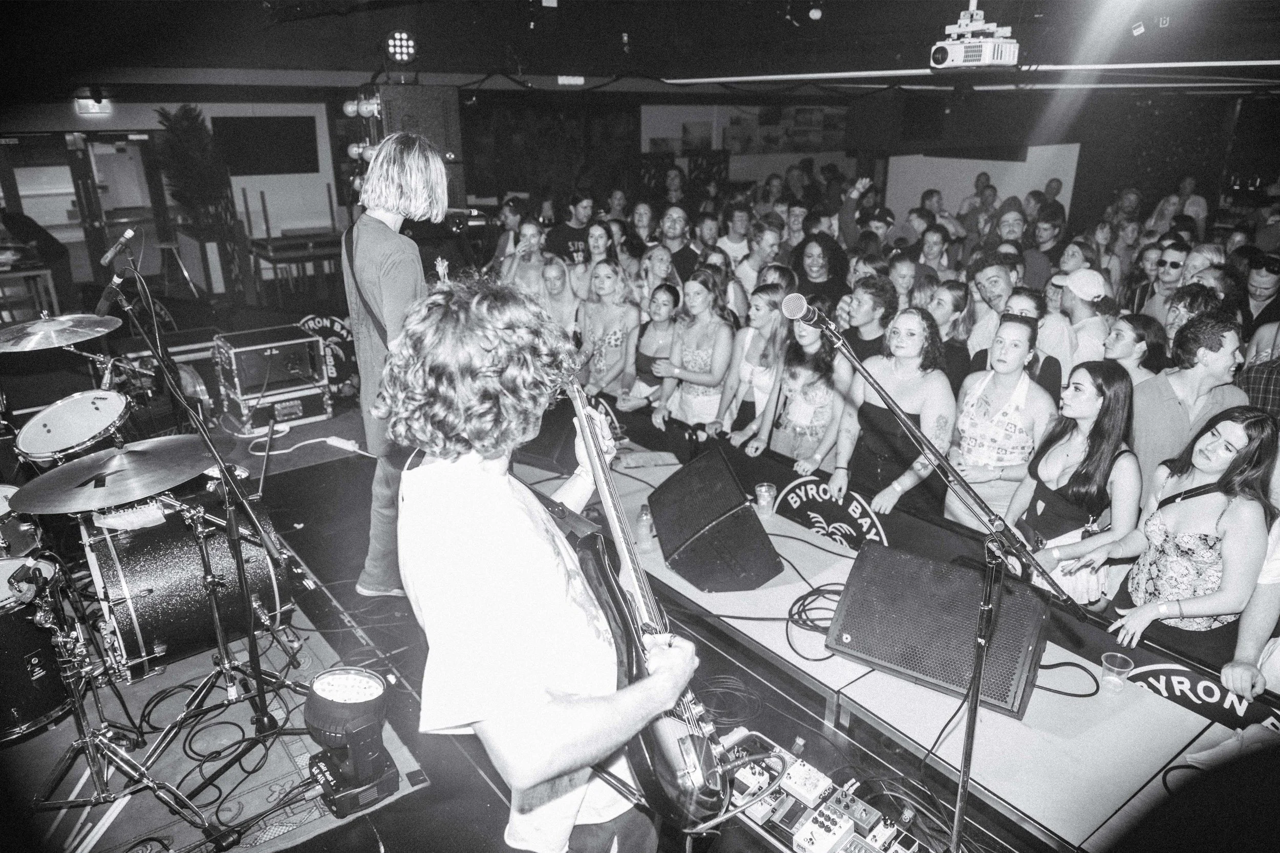 Live music performance at a concert with a band playing on stage and a large audience watching.