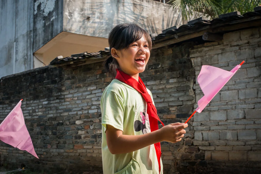  Students waving flags to welcome the visitors. 學校安排學生列隊搖旗，歡迎香港來到的慈善團體。
