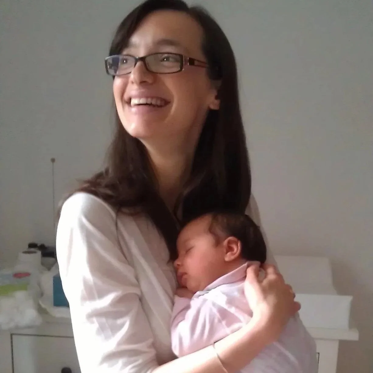 A smiling birth and postpartum doula holding a newborn baby in her arms