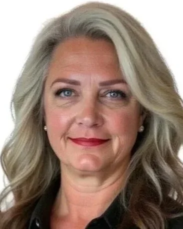 A woman with long gray hair, blue eyes, and red lipstick, smiling at the camera.