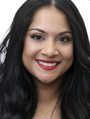A young woman with long black hair, smiling, wearing makeup, and a red lipstick, against a plain white background.