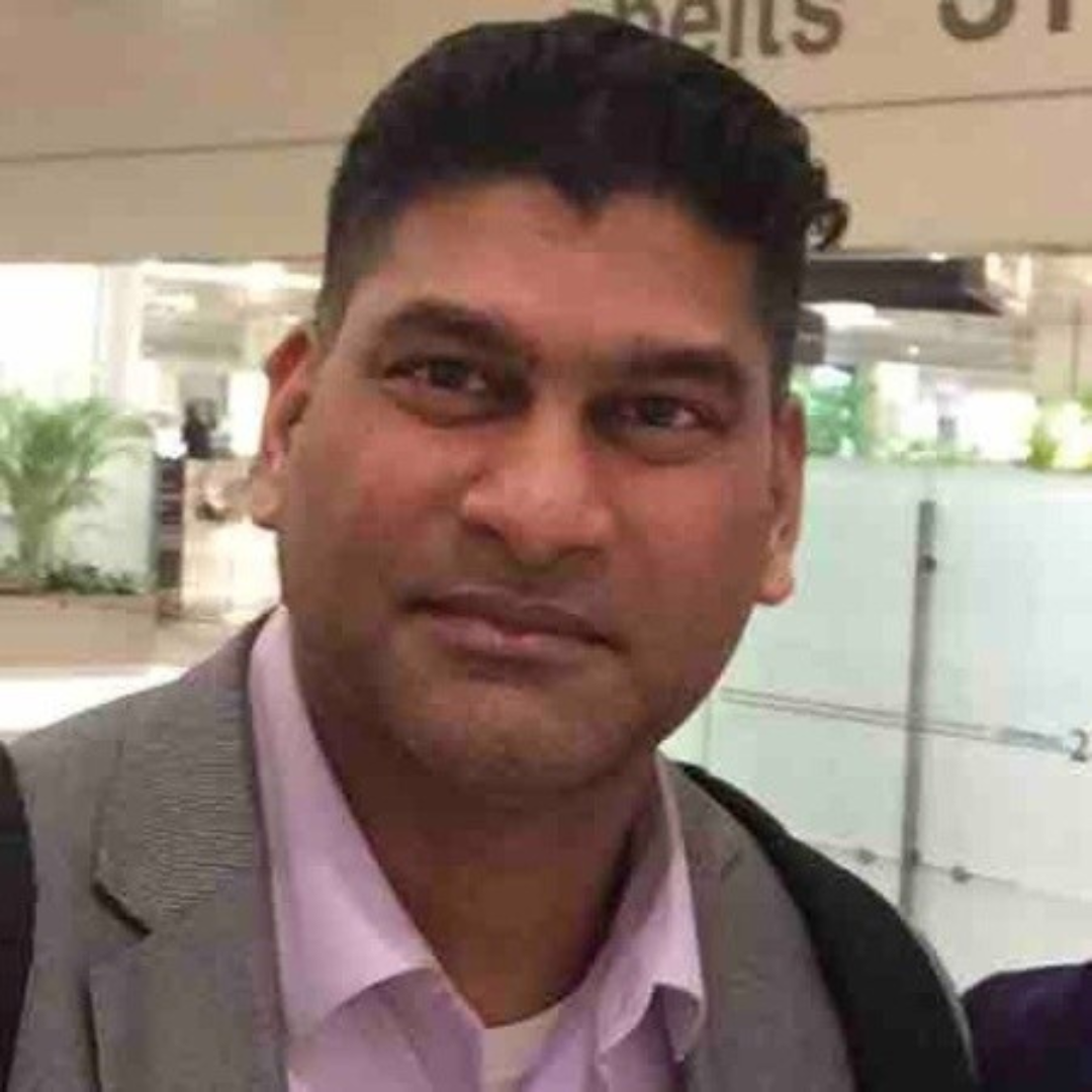 Man in gray suit with pink shirt at airport