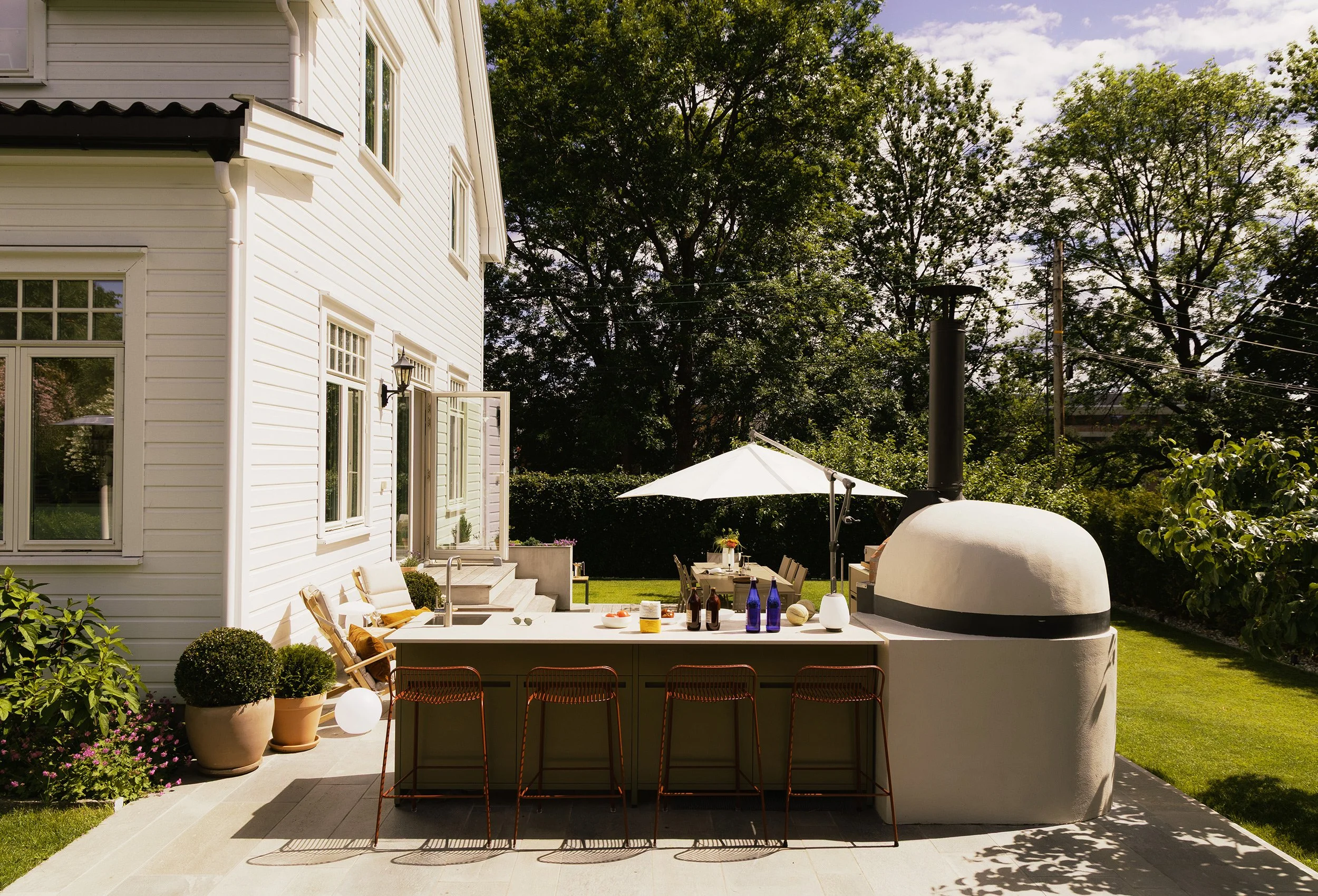 Øvre terrasse med utekjøkken, sitteplasser og integrert pizzaovn.