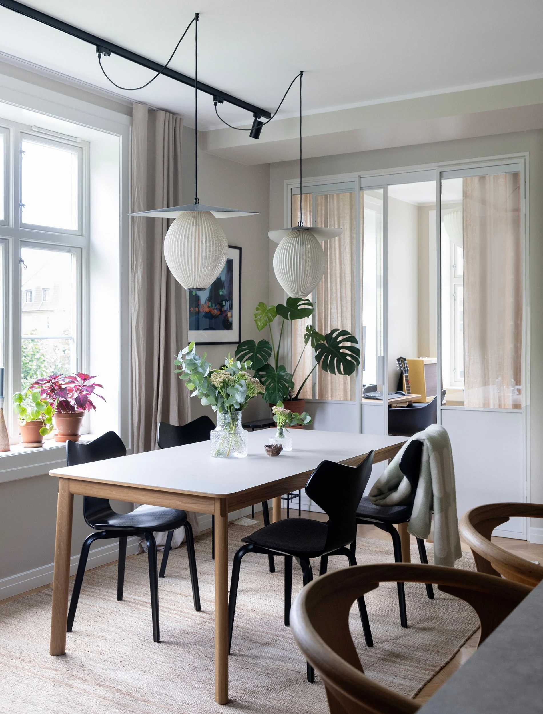 Spisesone med store vinduer og glassfelt mot tilstøtende rom.
