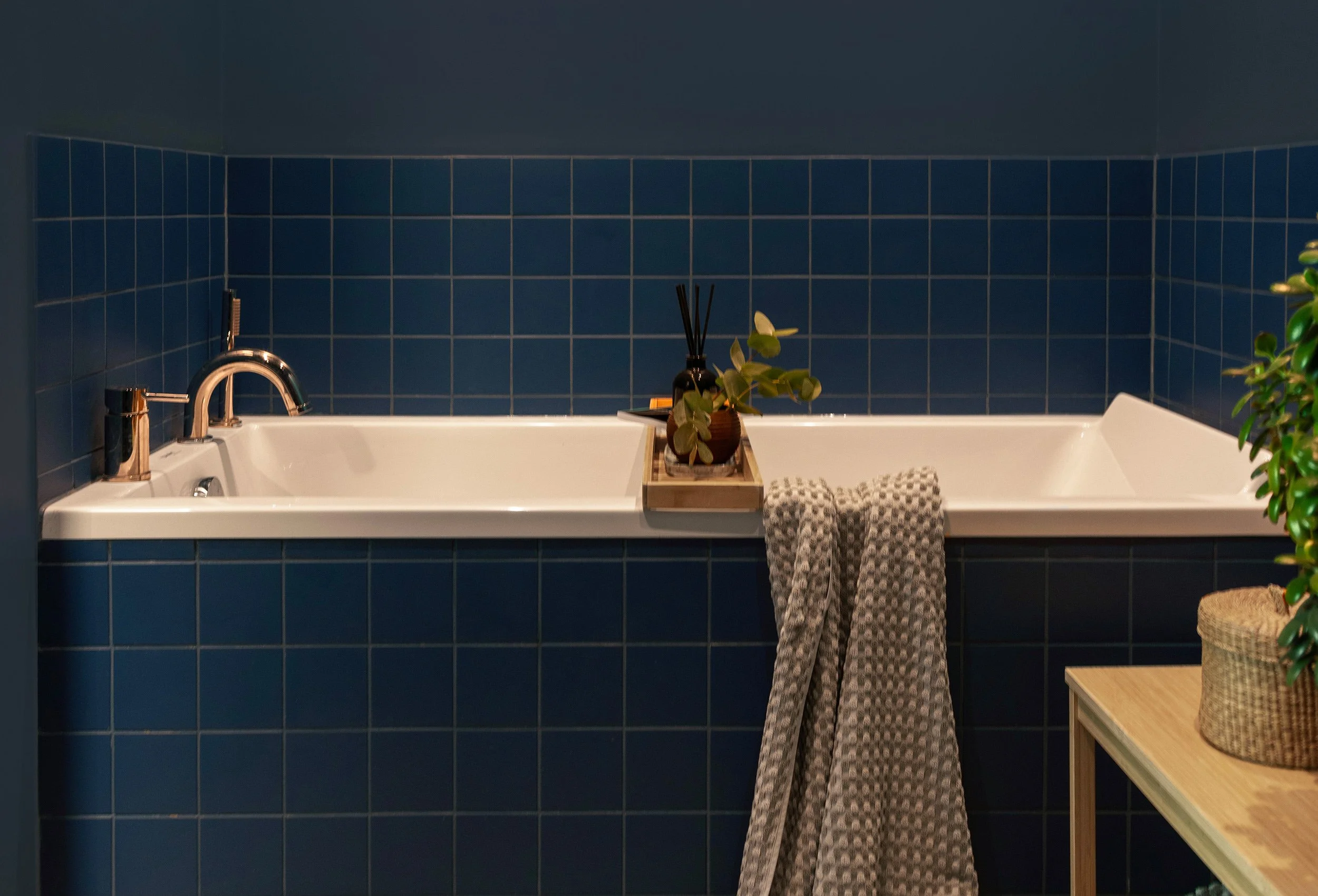 Innbygget badekar omgitt av blå fliser i familiens bad.