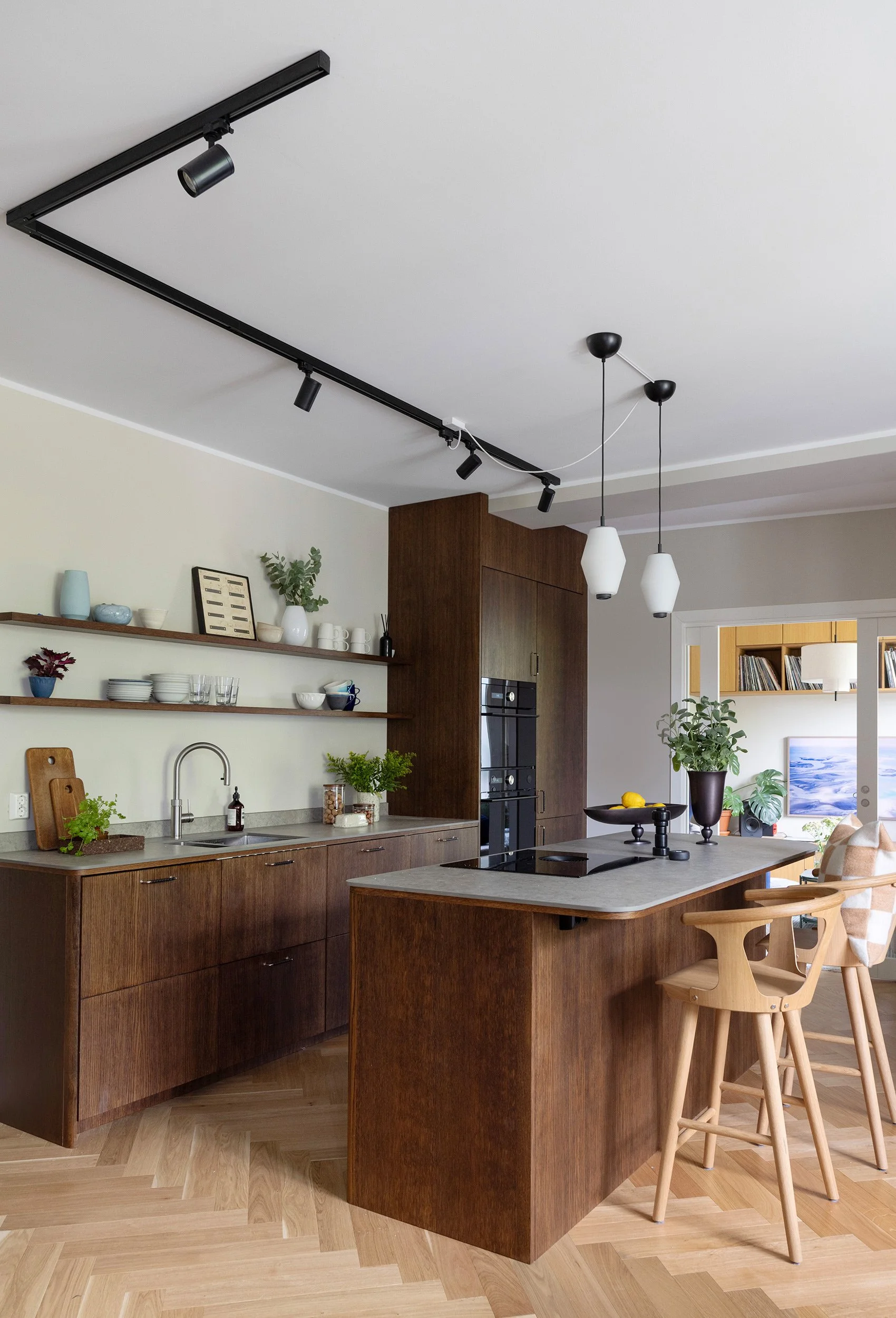 Kjøkken i mørkbeiset tre med stor øy og herringbone-parkett.