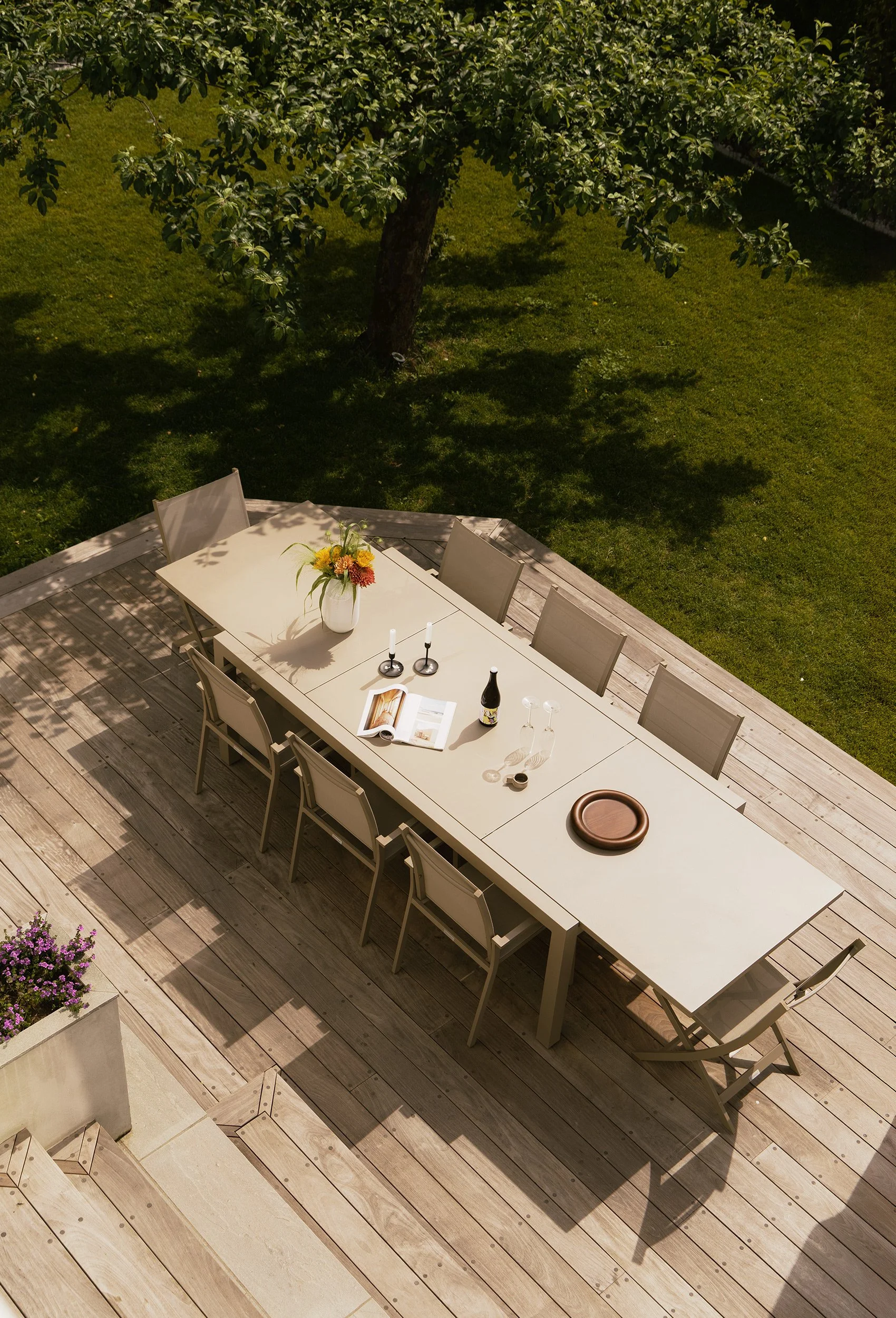 Nedre terrasse i tre med langbord og nær kontakt med hagen.