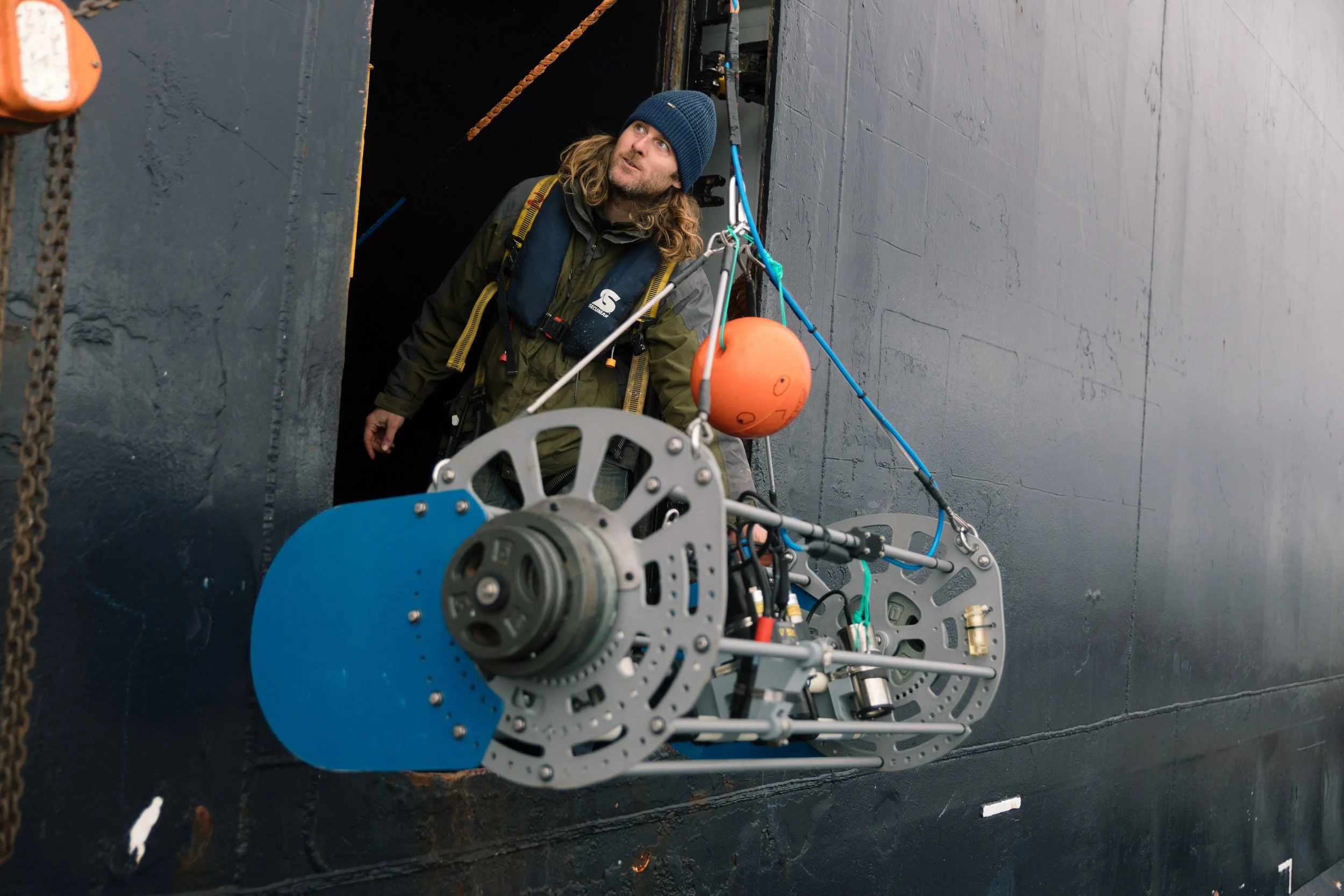 researcher with subsea tow camera frame exiting vessel door