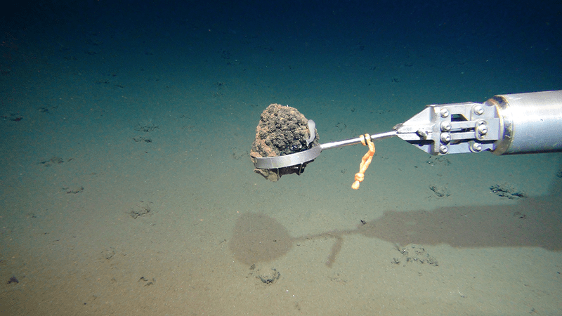 rov arm holding a rock underwater