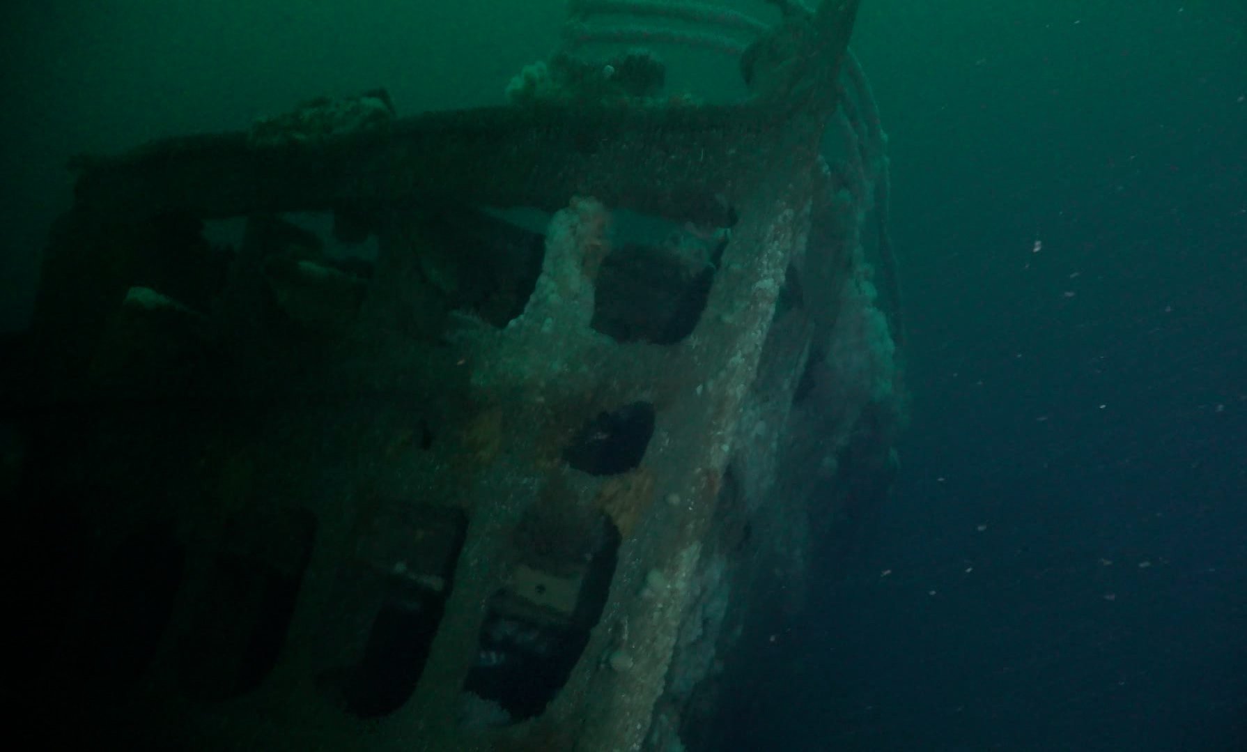 Bow of a sunken ship in murky water.
