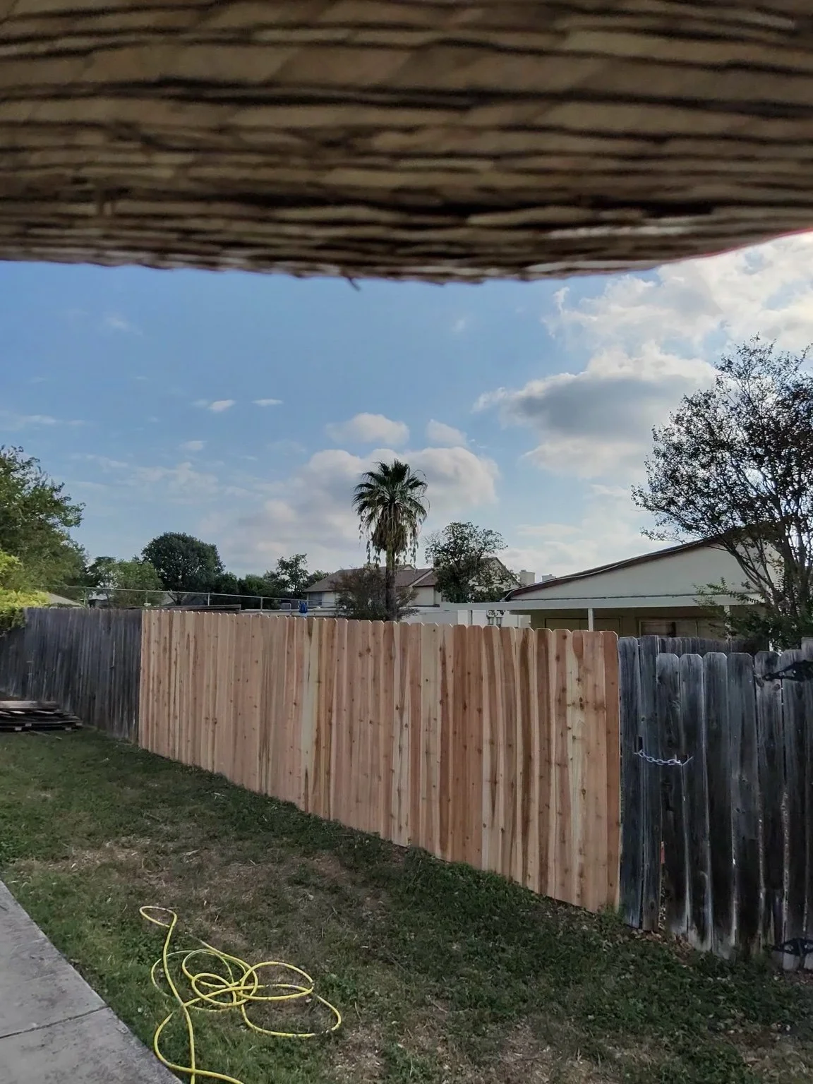 After: New cedar pickets and rails in the repaired fence section at a San Antonio apartment complex.