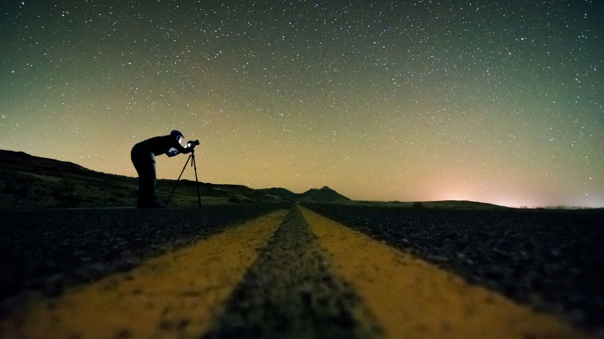 Man standing on road and looking through telescope