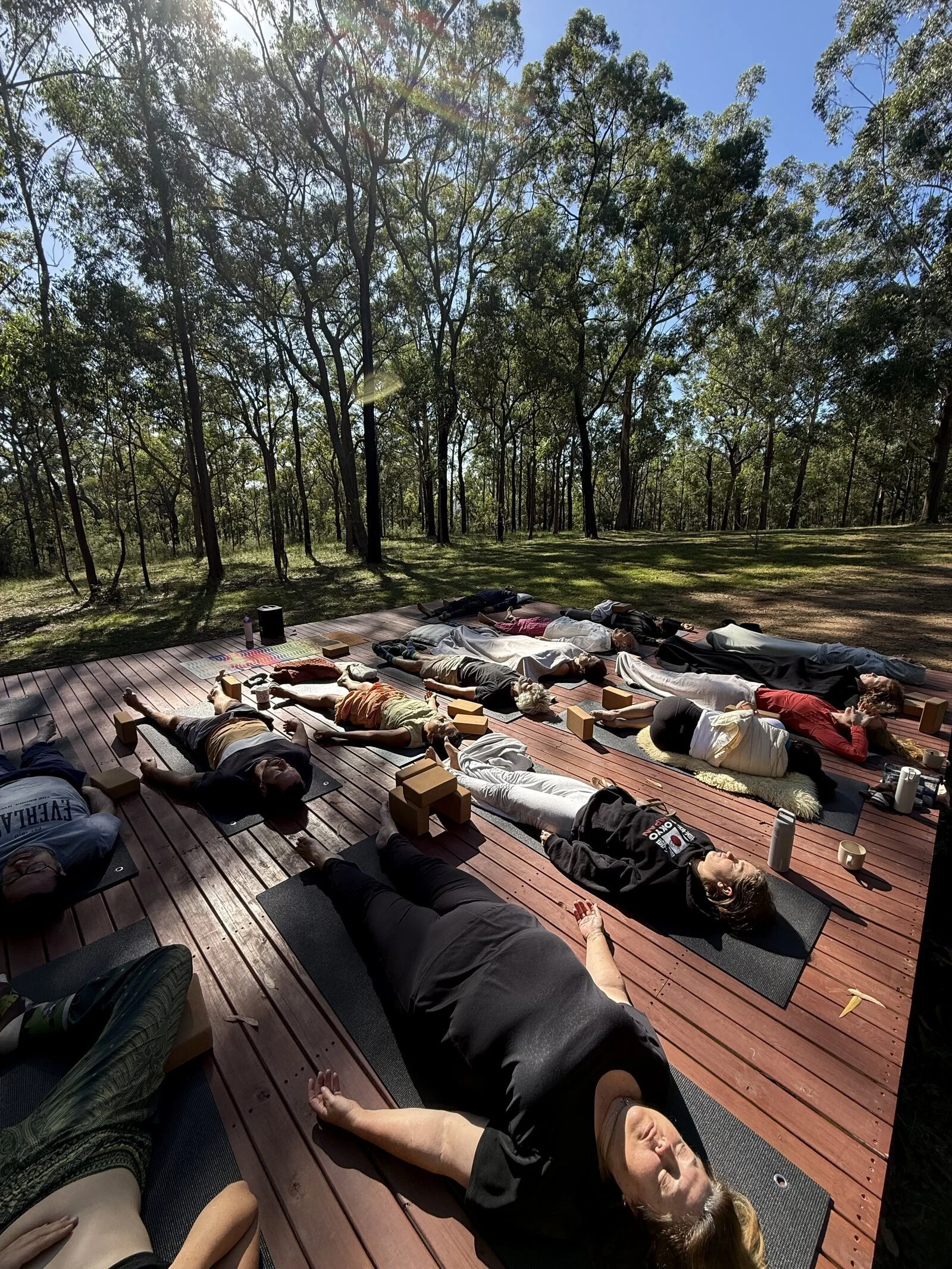 Guests resting on the outdoor yoga deck at Thrive Retreats, surrounded by trees