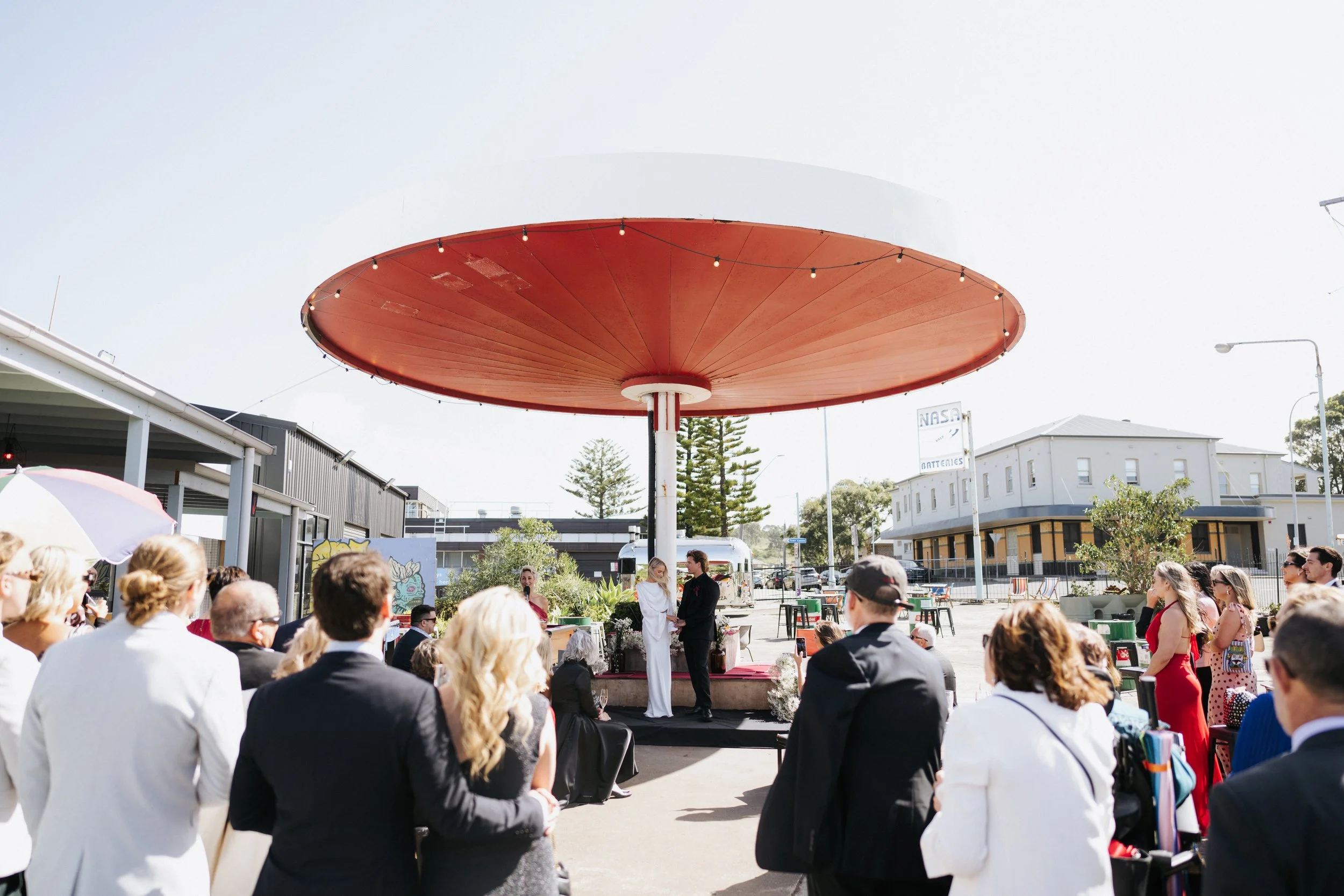 Jacqua Celebrant conducting Maggie and Dane’s wedding ceremony at Port Kembla Servo. Photo credit: Damien Milan