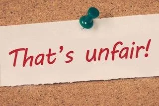 scrap of paper that says that's unfair pinned to cork board