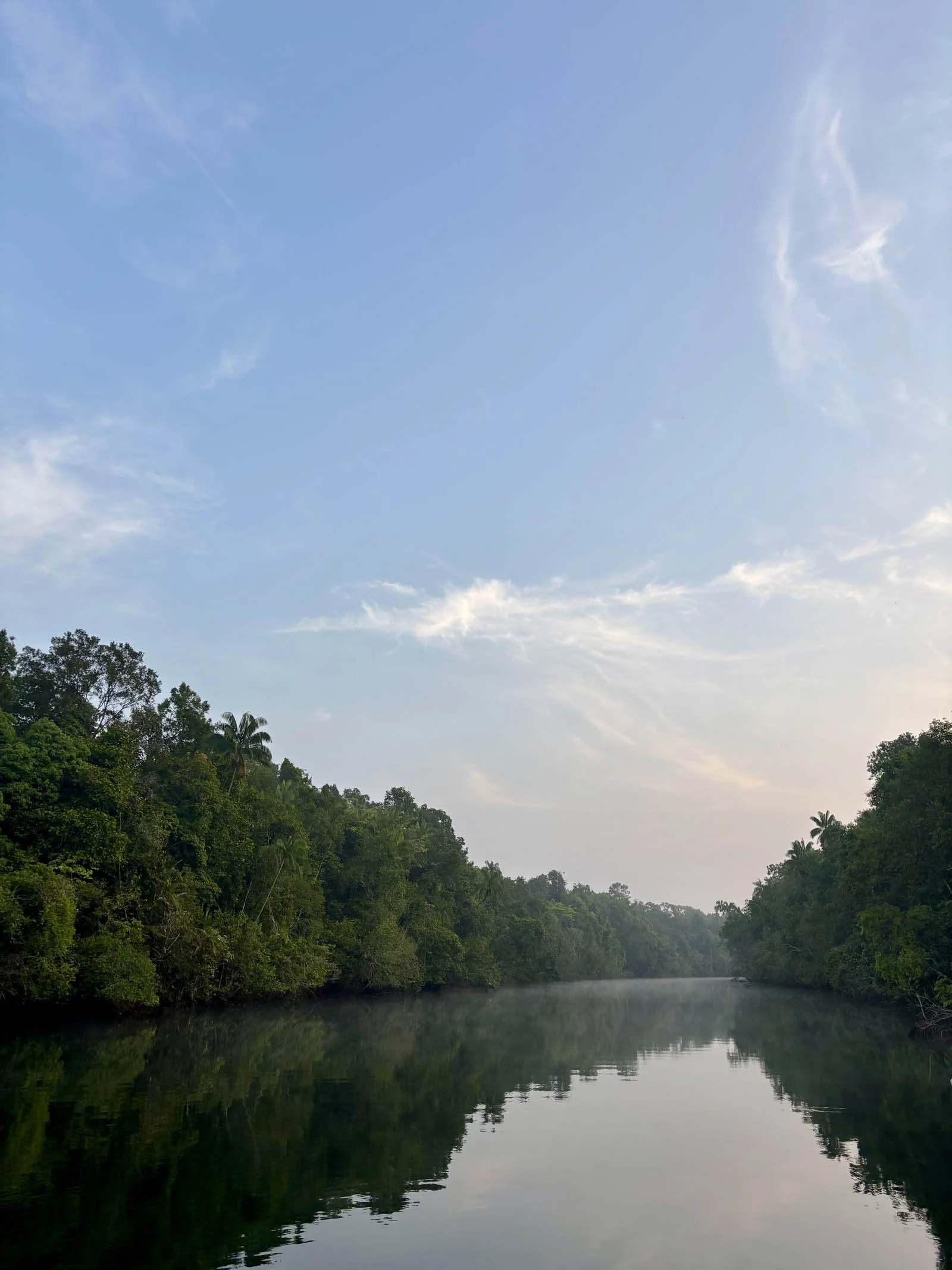  Wispy clouds are reflected in the glass-like surface of the river 