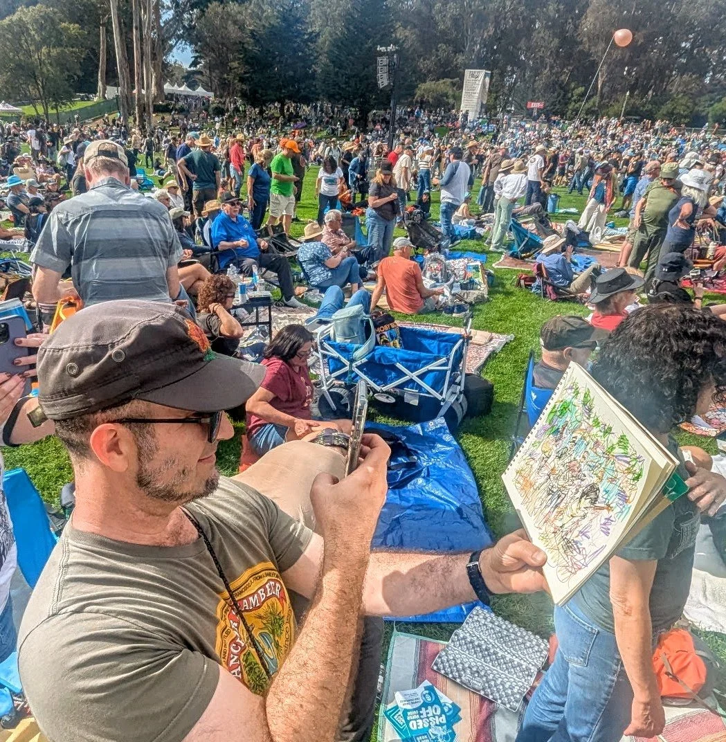 Todd takes a picture of a drawing standing in front of a large crowd in Golden Gate Park