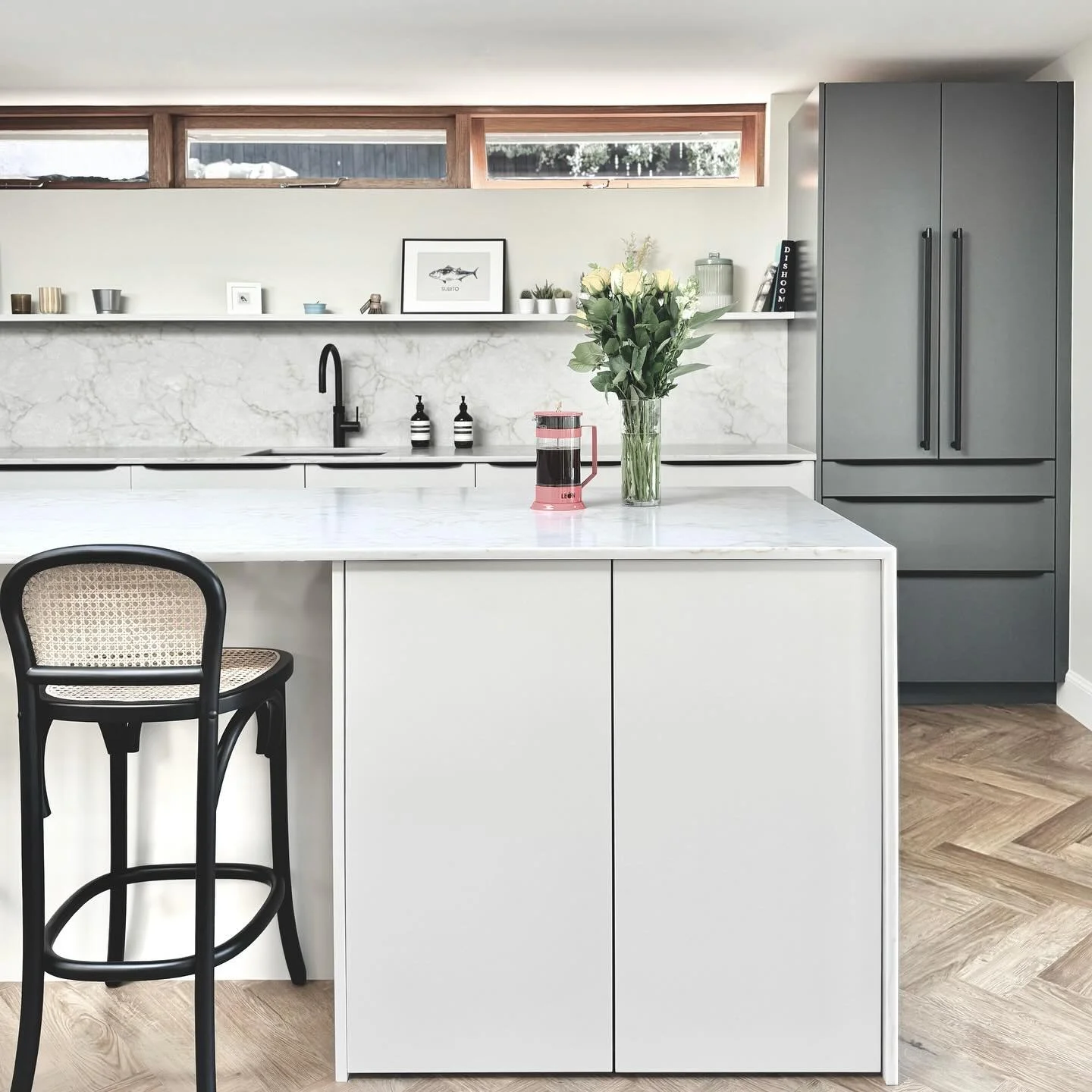 Simple yet impactful. Clean lines, timeless materials and uncompromising quality. 

Cabinetry: Warm grey slab doors with Verde Comodoro detailing
Work surfaces: 20mm Mont Blanc Quartz
Hob: Bora Pure venting hob 
Appliances: Neff suite
Tap: Quooker Fl