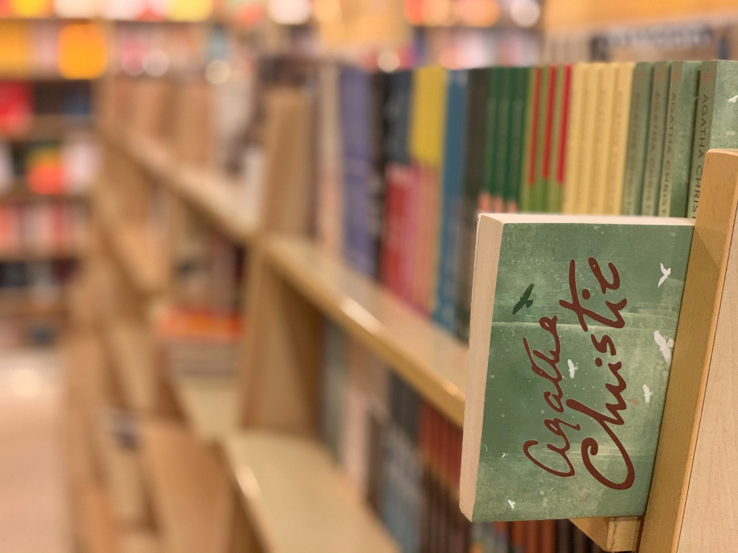 A long book shelf in the background with a copy of an Agatha Christie novel in the foreground.