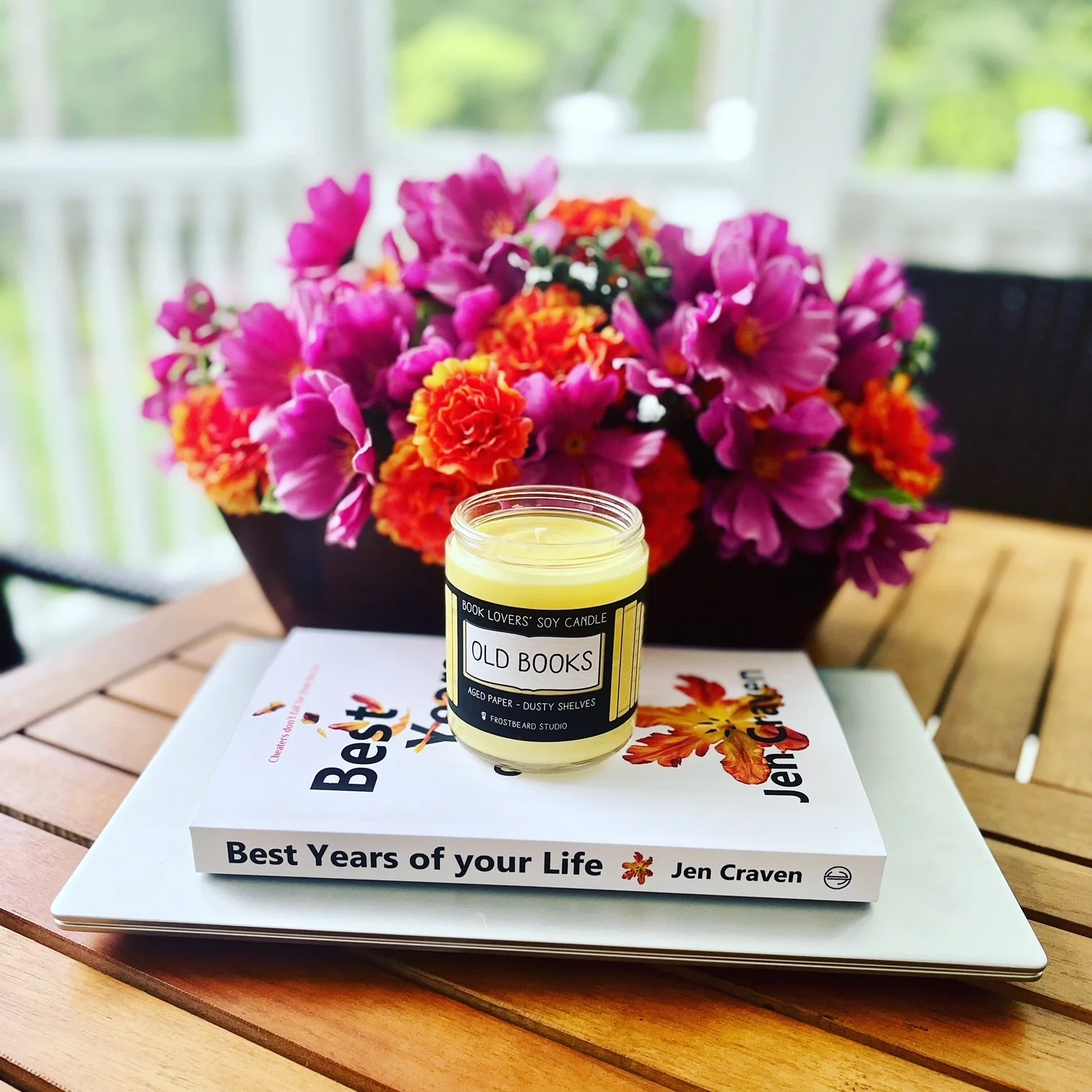 The novel, Best Years of Your Life, on a table with flowers and a bookish candle.